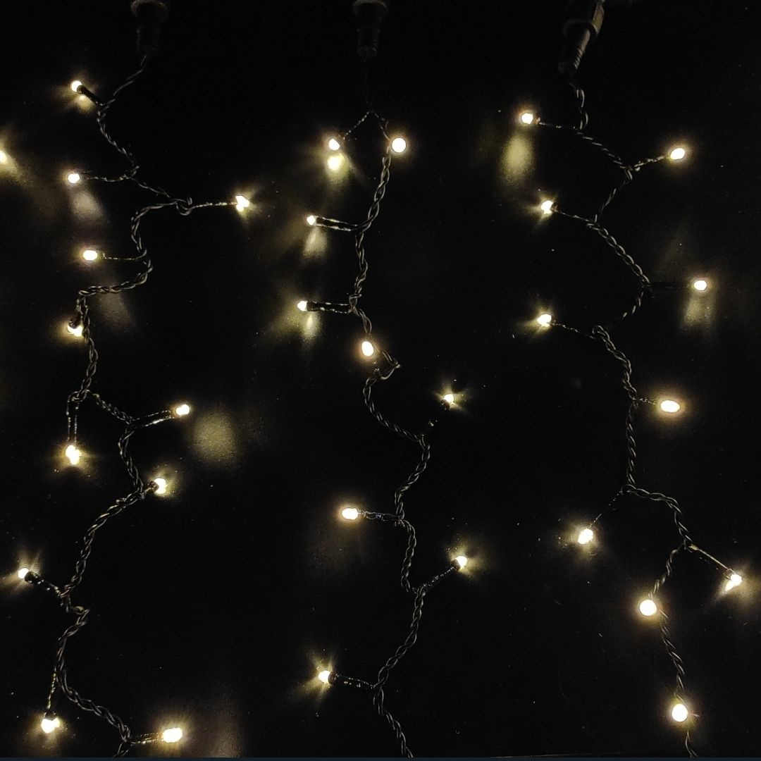 Tres tiras verticales de luces LED de color blanco cálido cuelgan sobre un fondo oscuro.