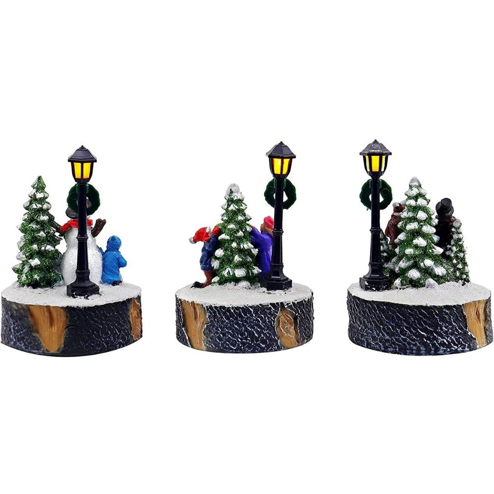 Tres dioramas navideños con árboles, farolas y figuras sobre bases con textura de madera.