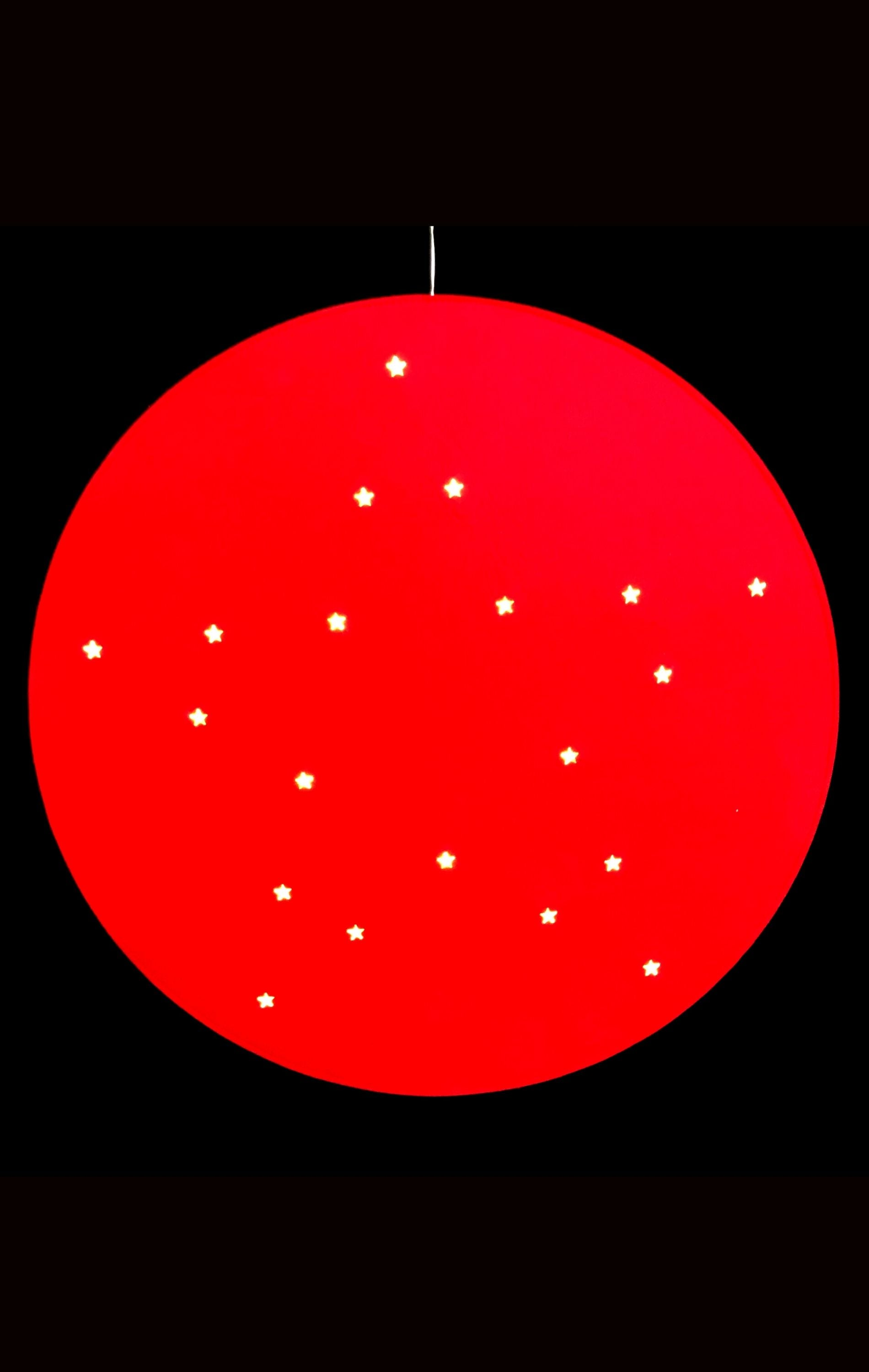 Un gran círculo rojo con estrellas blancas brillantes sobre un fondo negro.