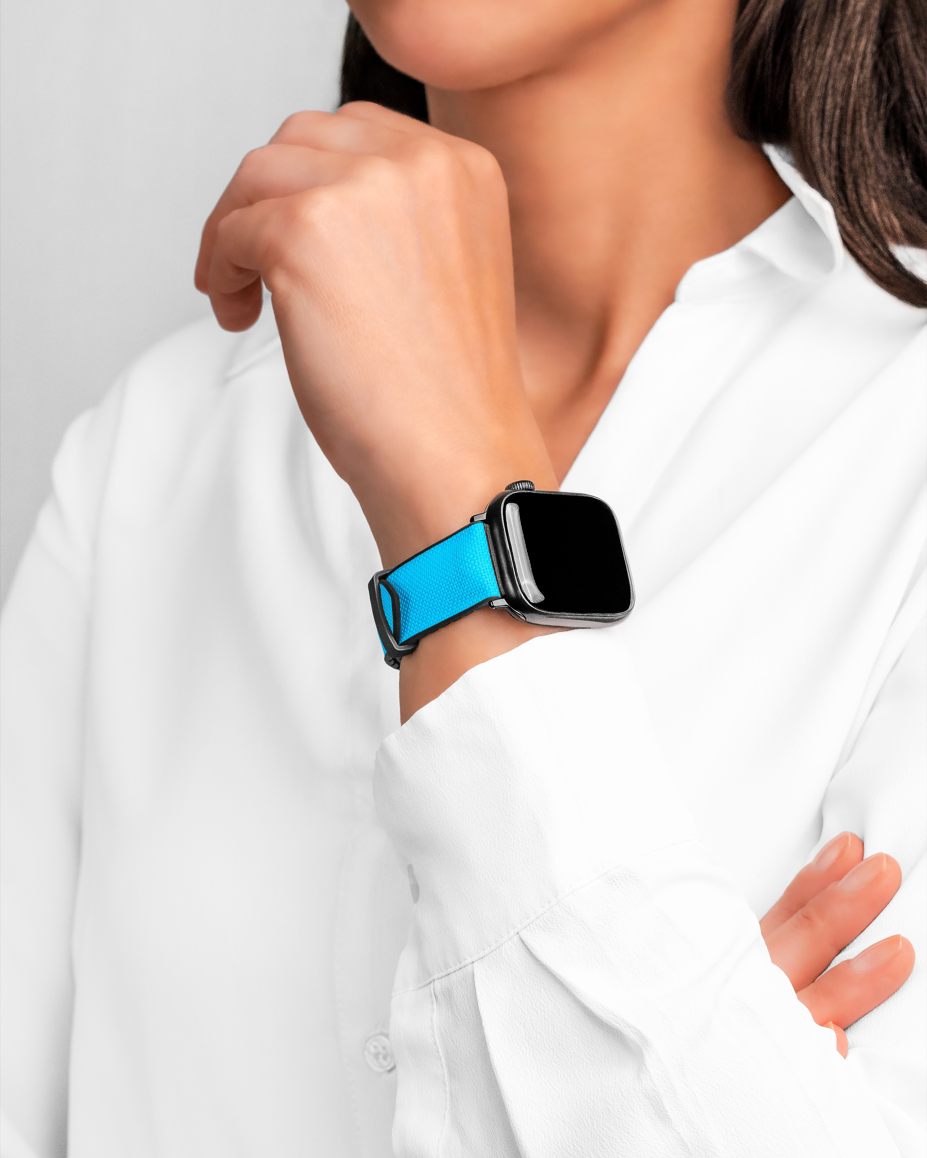Eine Frau in weißem Hemd trägt eine Smartwatch mit leuchtend blauem Armband.