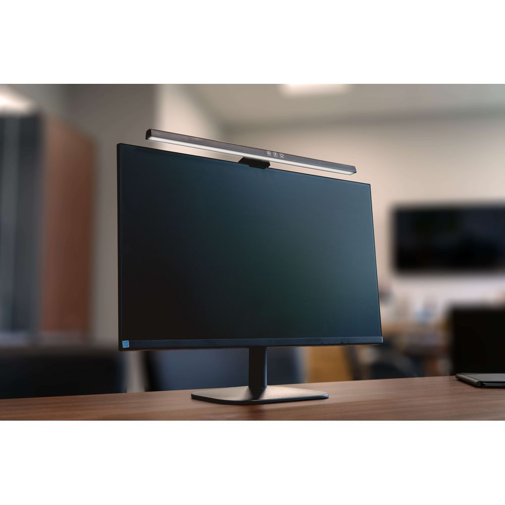 Eine Monitor-Hängelampe leuchtet den Bildschirm auf einem Schreibtisch aus.