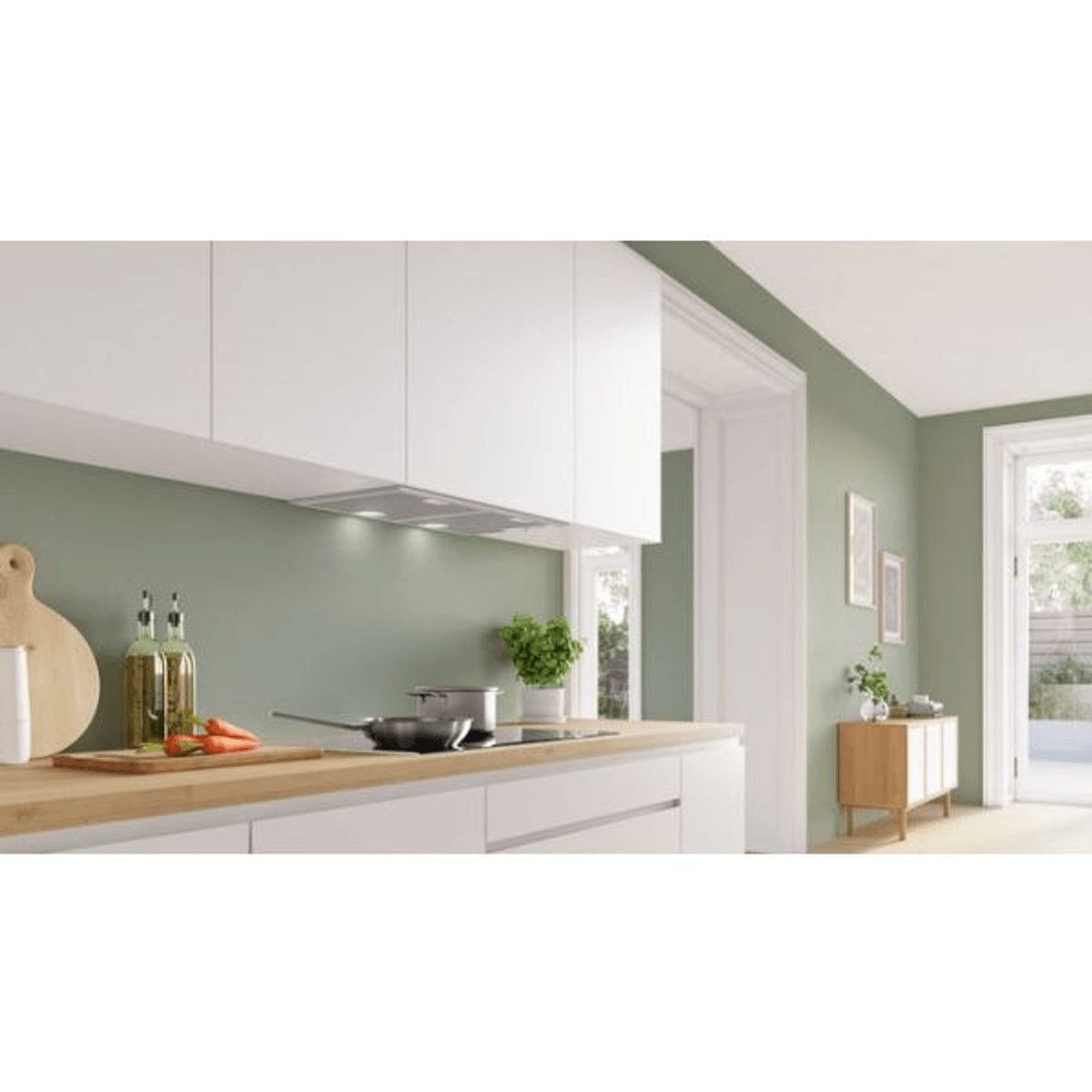 Una cocina moderna con armarios blancos, paredes verdes, encimeras de madera y estufa con sartén.