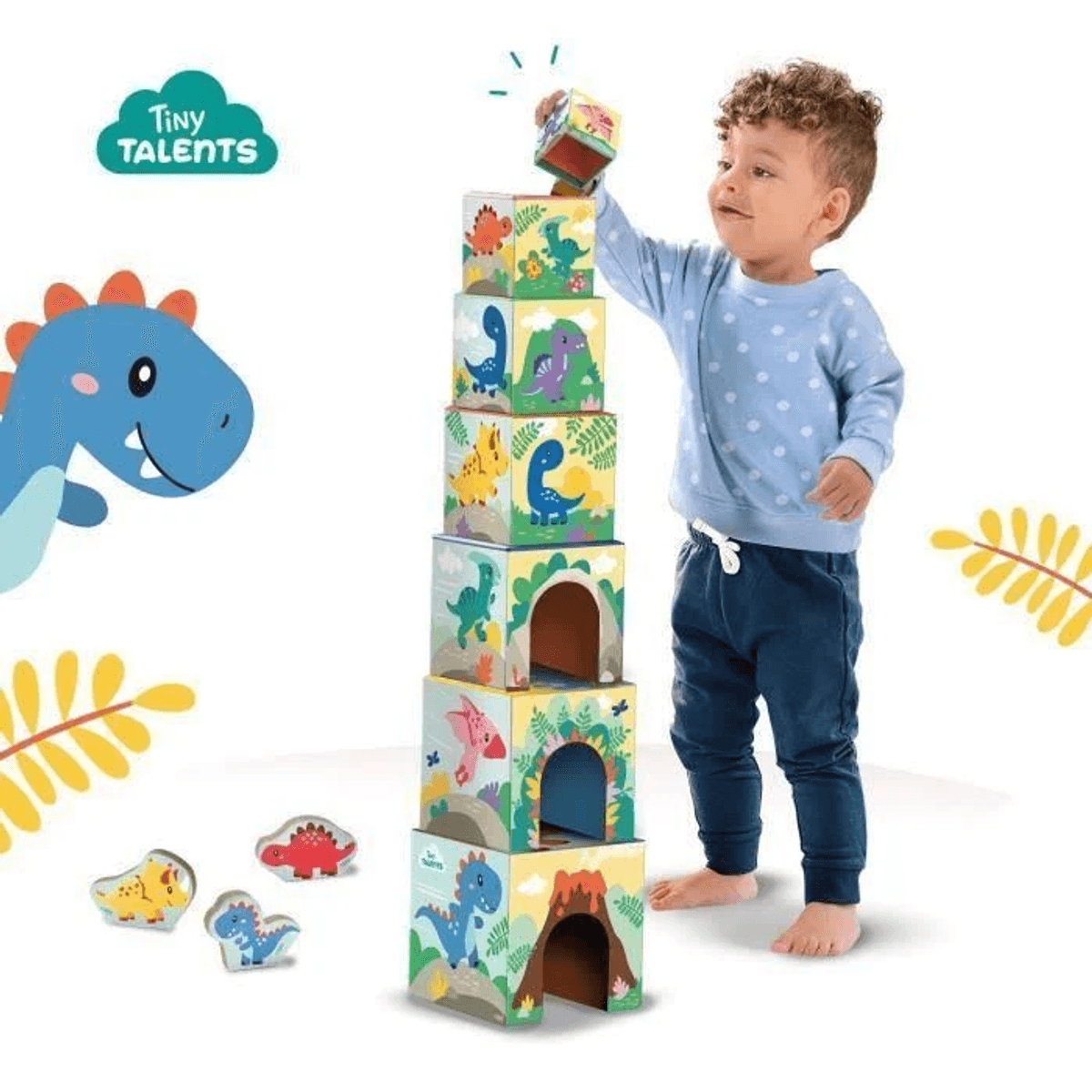 Un niño pequeño con ropa azul apila bloques de dinosaurios coloridos, con una ilustración de dinosaurio azul cerca.