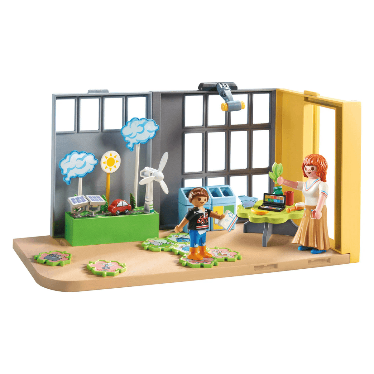 Playmobil-Set mit zwei Figuren, einem grünen Schreibtisch, Solarpaneelen und einer Windkraftanlage in einem Öko-Klassenzimmer.