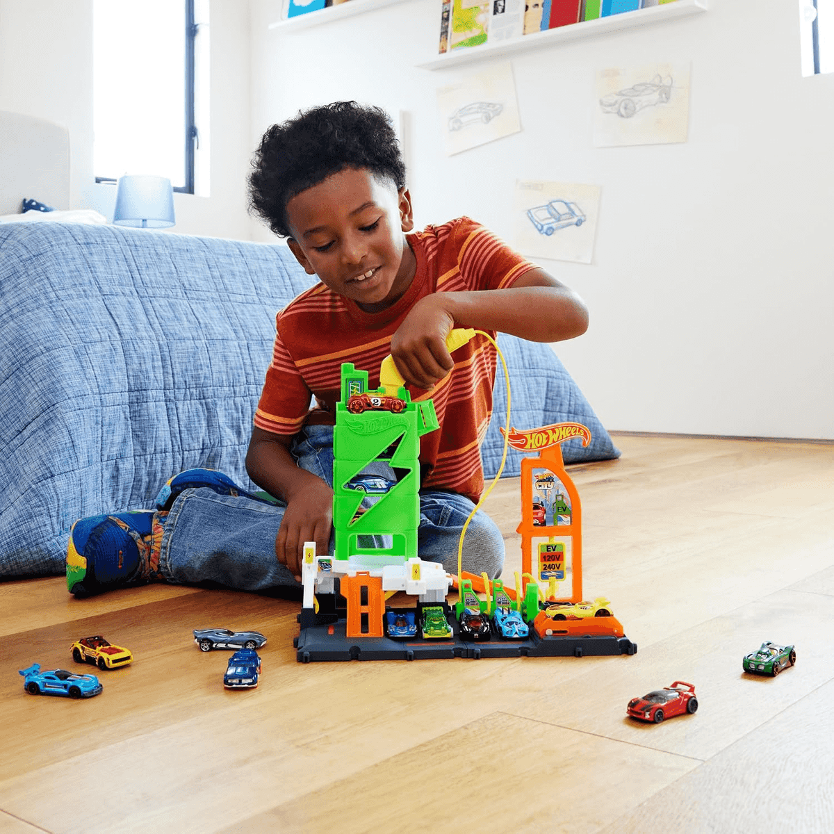 Un niño pequeño jugando con un garaje de juguete y carros de juguete.