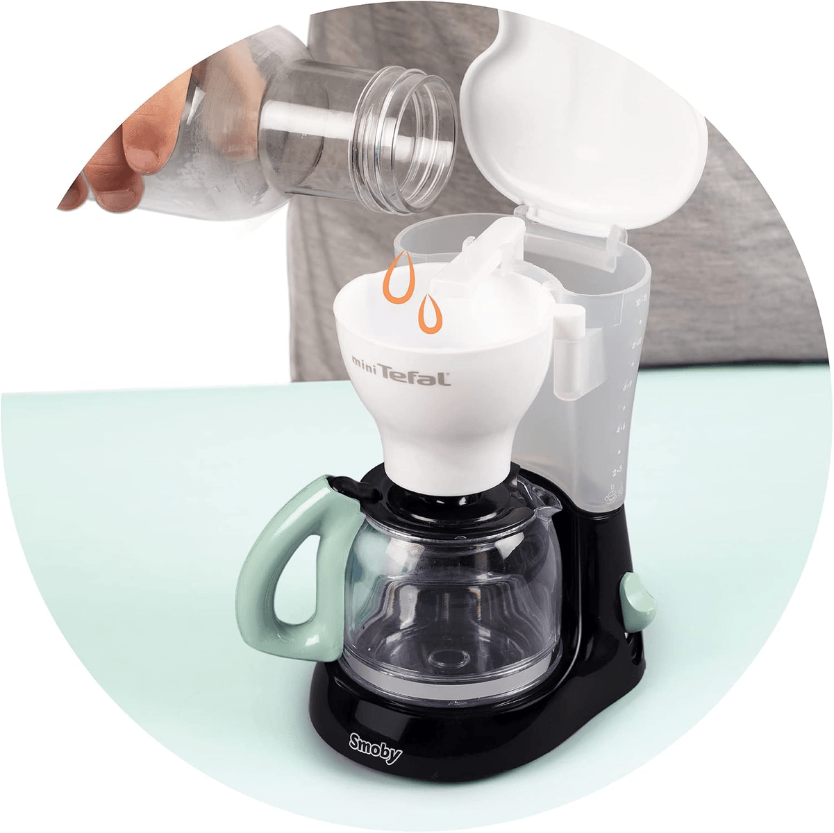 Se vierte agua de una botella en una cafetera de juguete blanca Tefal.