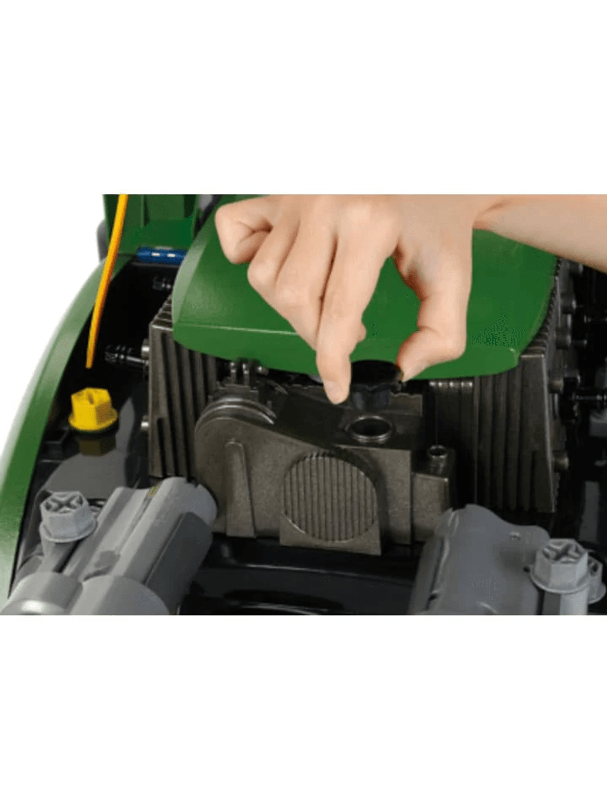 Una mano abre una tapa negra en el motor de una máquina verde y negra.