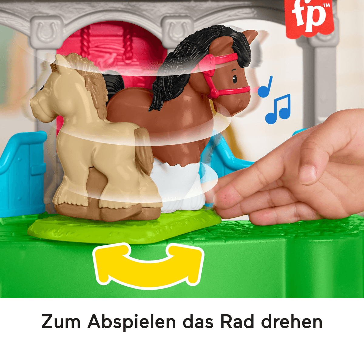 Hand dreht Rad an Spielzeugpferdestall mit zwei kleinen Pferden.