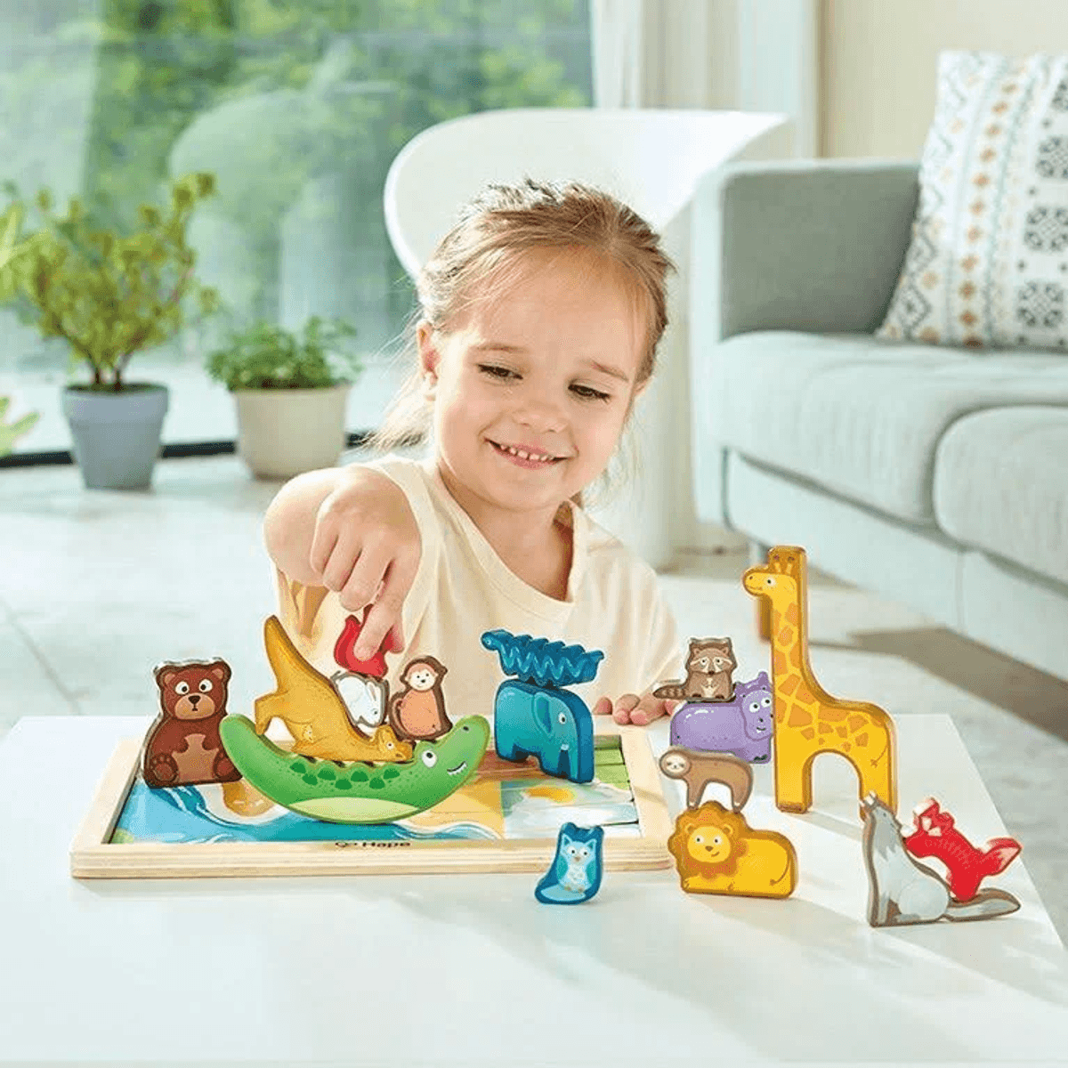 Una niña jugando con juguetes de madera coloridos de animales apilables en una mesa.