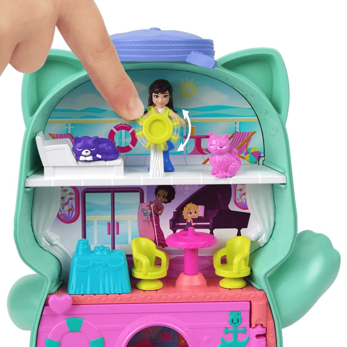 Un dedo presiona una pequeña casa de muñecas con forma de gato con figuras y muebles.