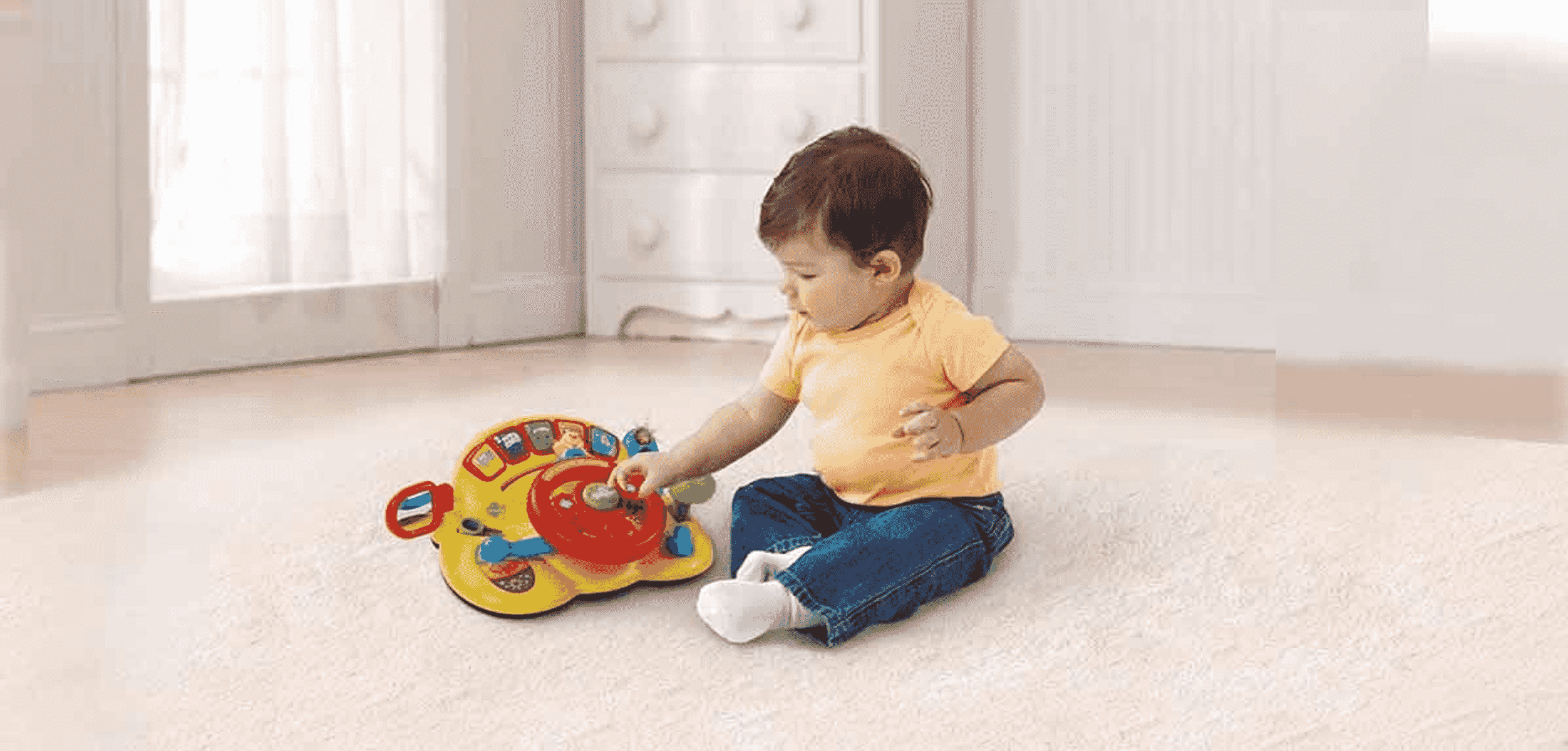 Niño pequeño sentado en la alfombra jugando con un juguete rojo y amarillo.