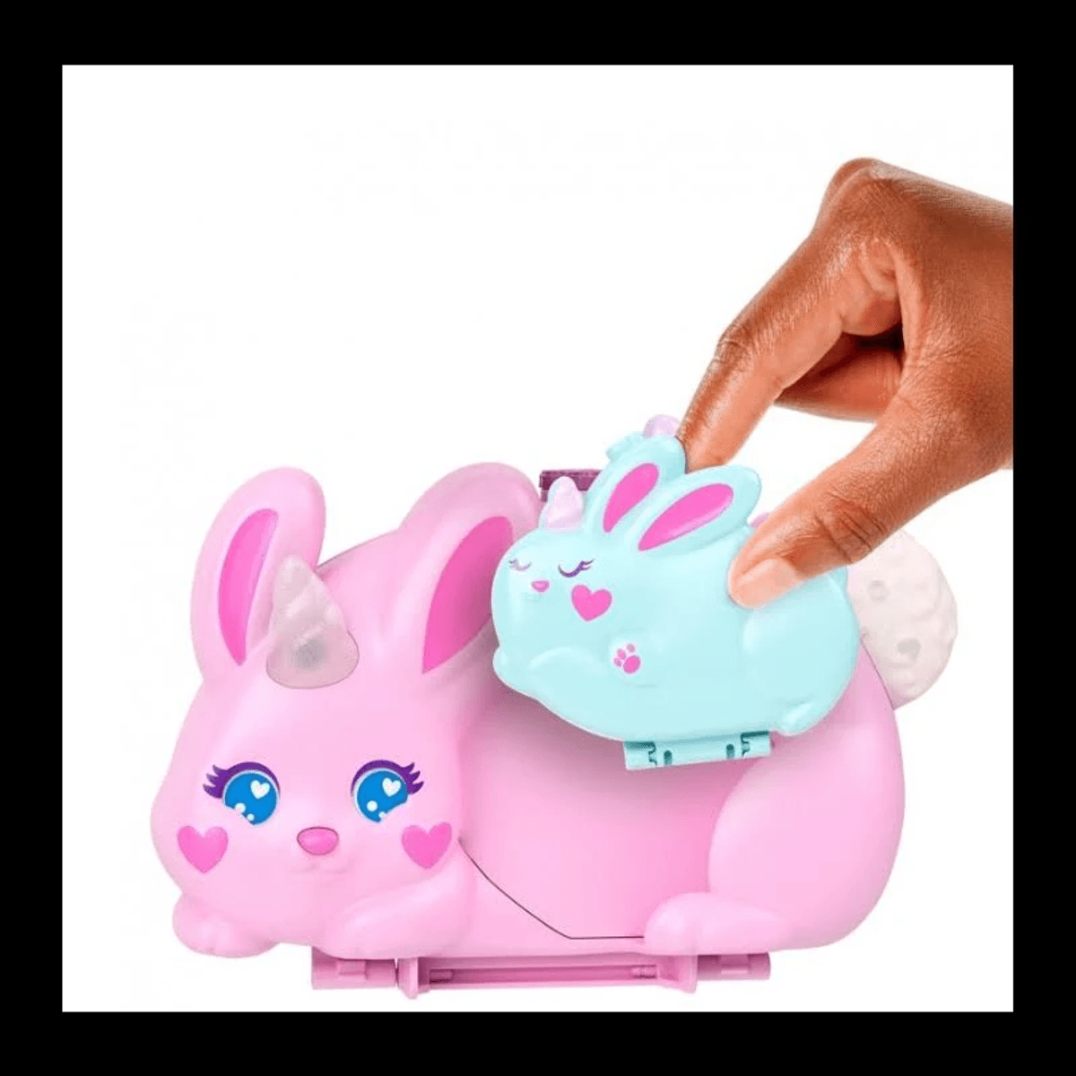 Una mano abre un pequeño compartimento de conejito azul en un gran conejo de juguete rosa con cuerno.