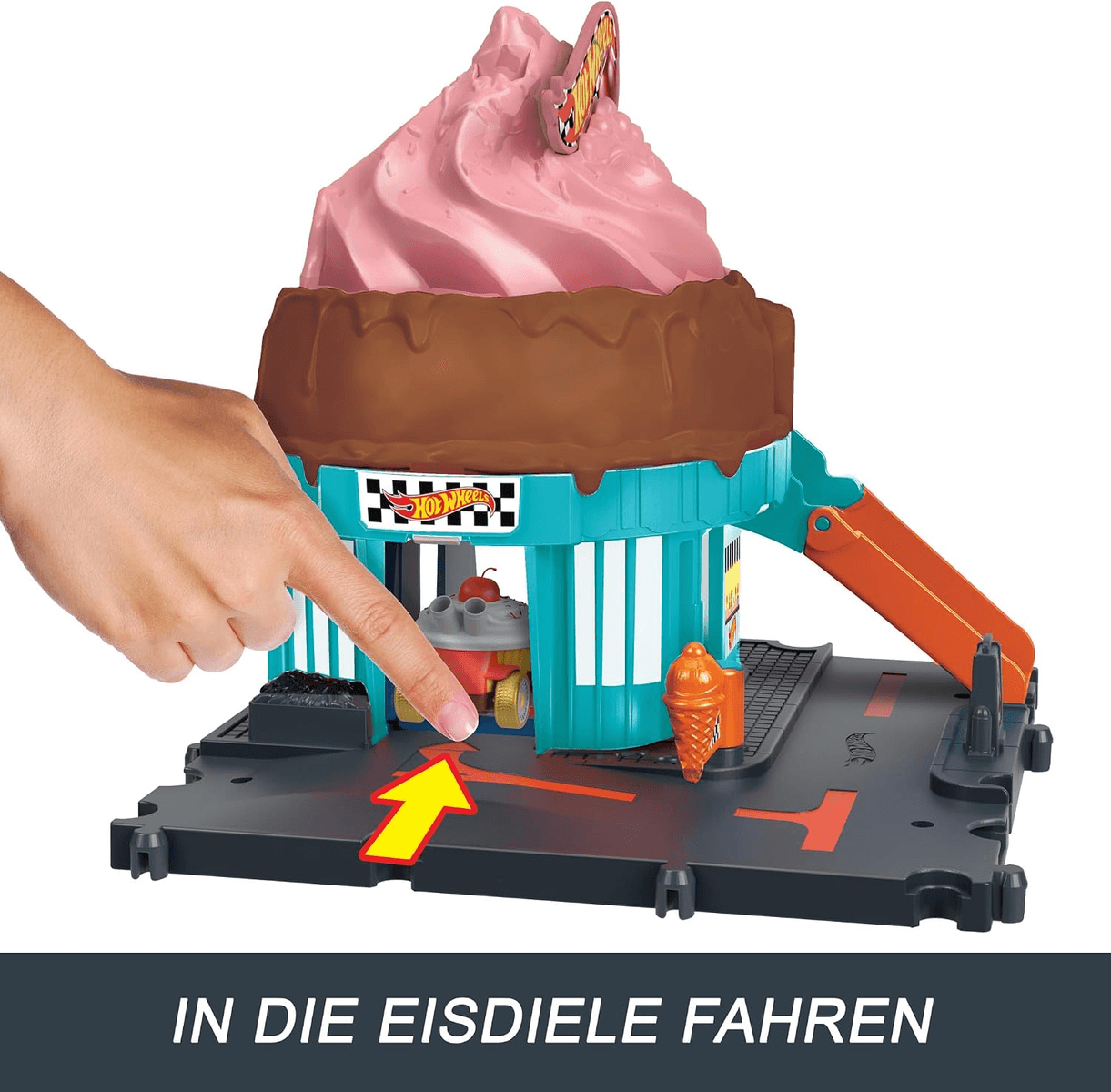 Una mano señala un colorido juego de heladería Hot Wheels con parte superior rosa y marrón.