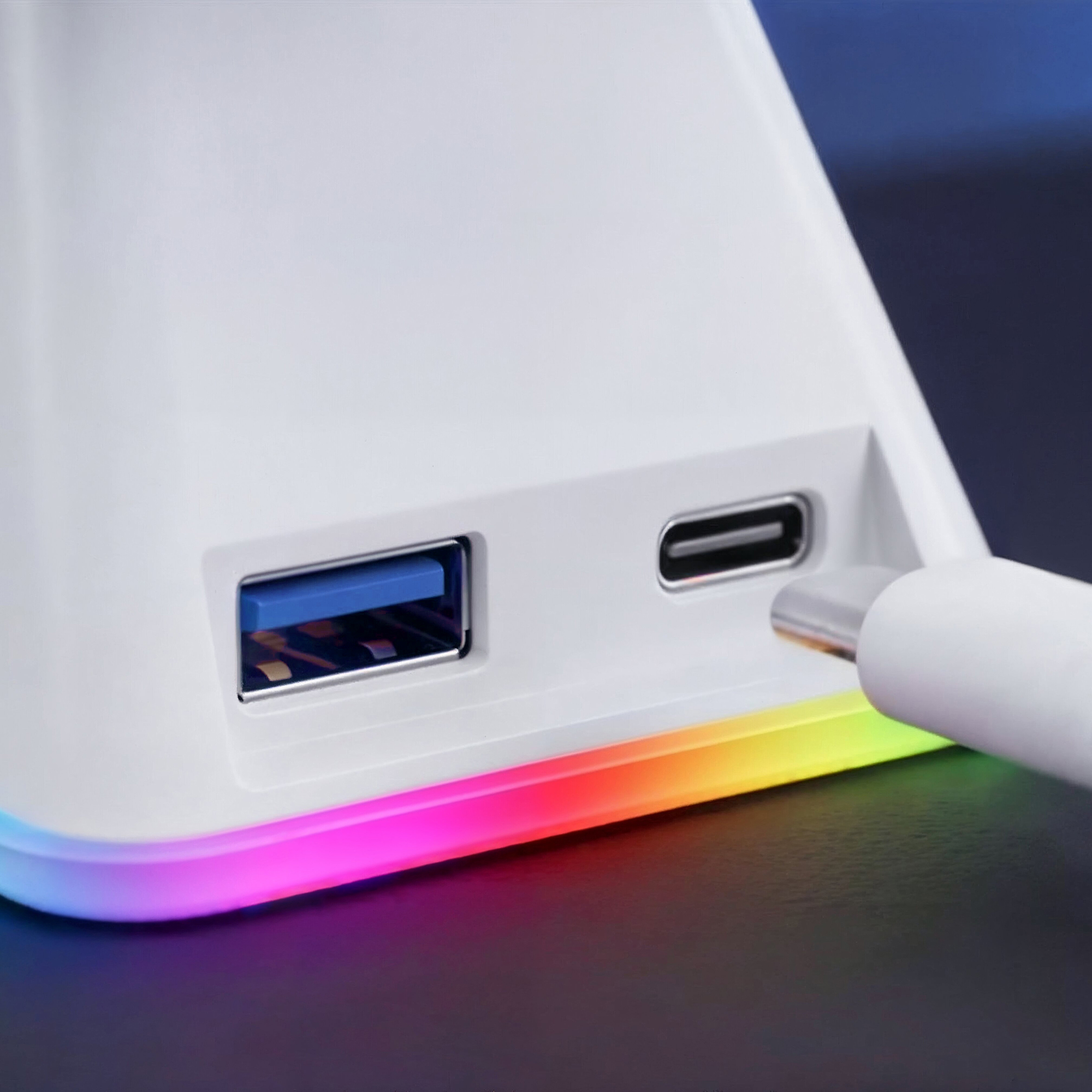 Primer plano de una estación de carga blanca con un puerto USB y una tira LED colorida en la parte inferior.