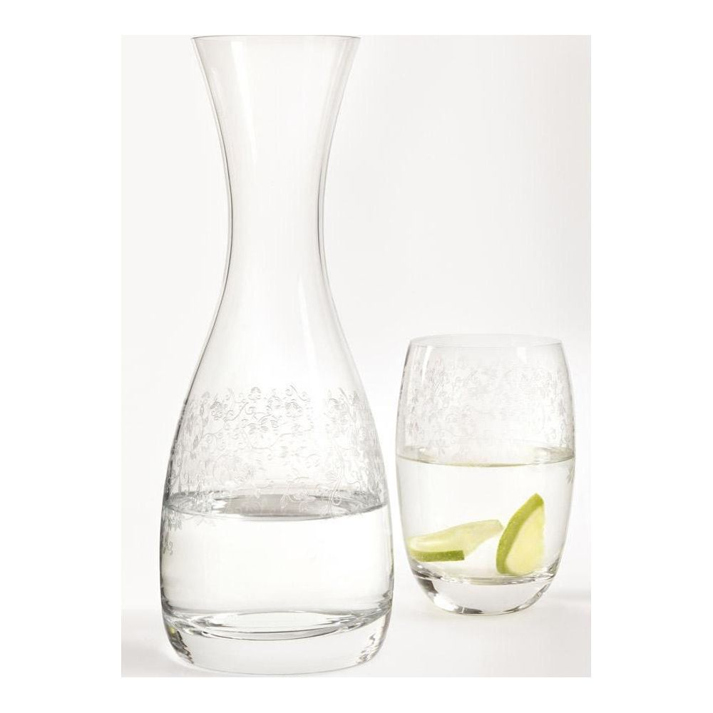 Eine Glasaraffe und ein Glas mit Wasser und Limettenscheiben vor weißem Hintergrund.