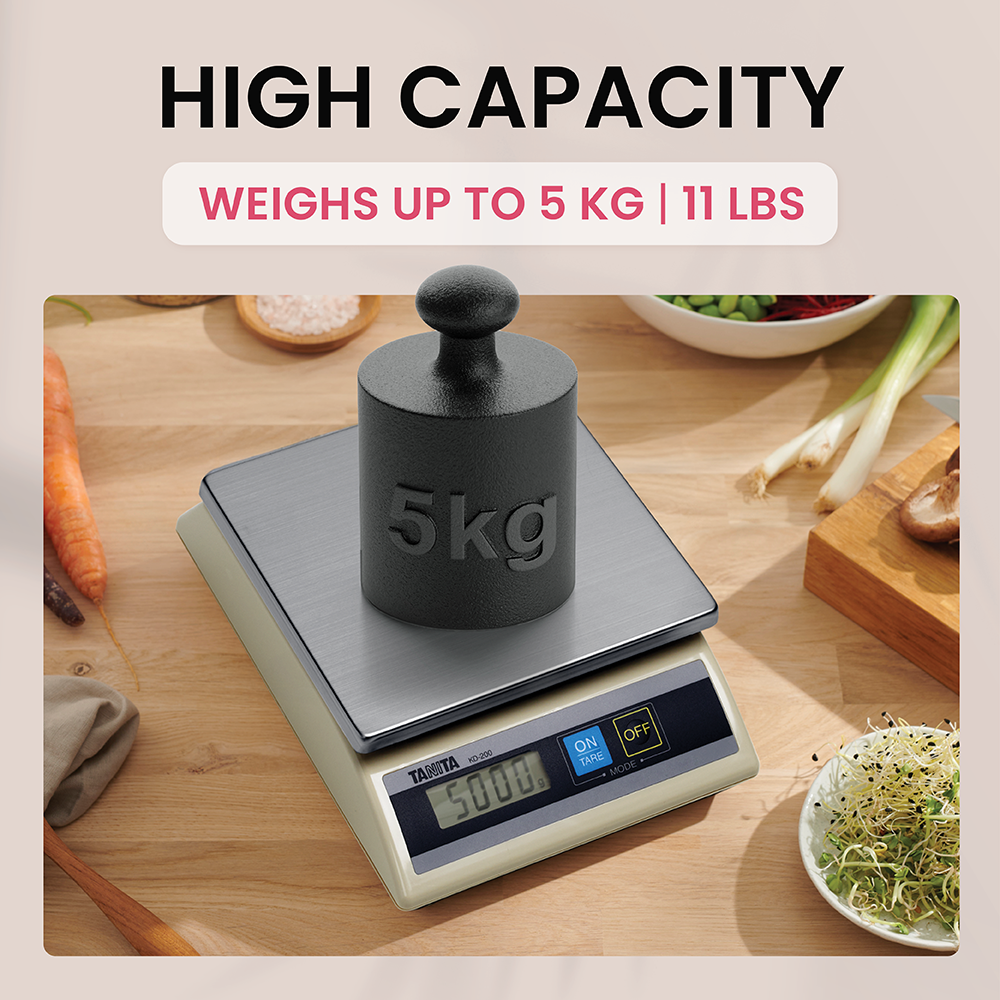 Eine digitale Küchenwaage hält ein 5-kg-Gewicht auf einem Holztisch mit Gemüse.