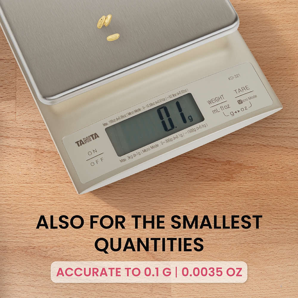 A kitchen scale on a wooden surface displays 0.1 grams with small grains of rice on it.