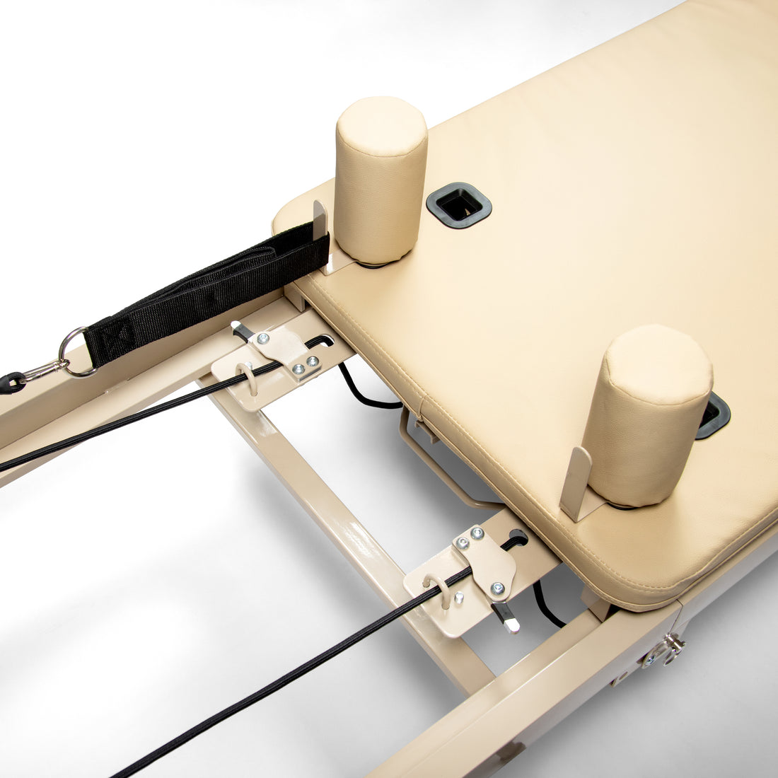 Primer plano de un reformador de pilates beige con cuerdas y soportes.