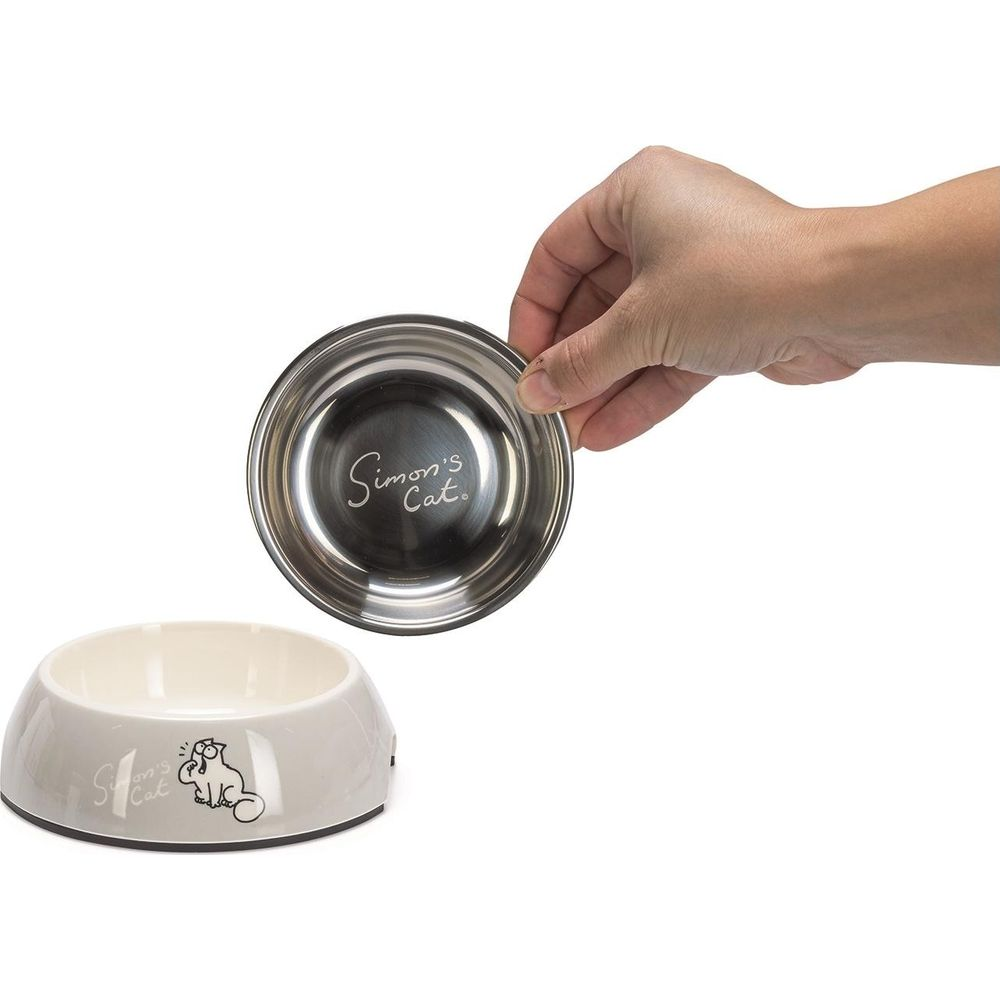Eine Hand hält einen Edelstahl-Futternapf über einem beigen Napf mit Simon's Cat-Logo.