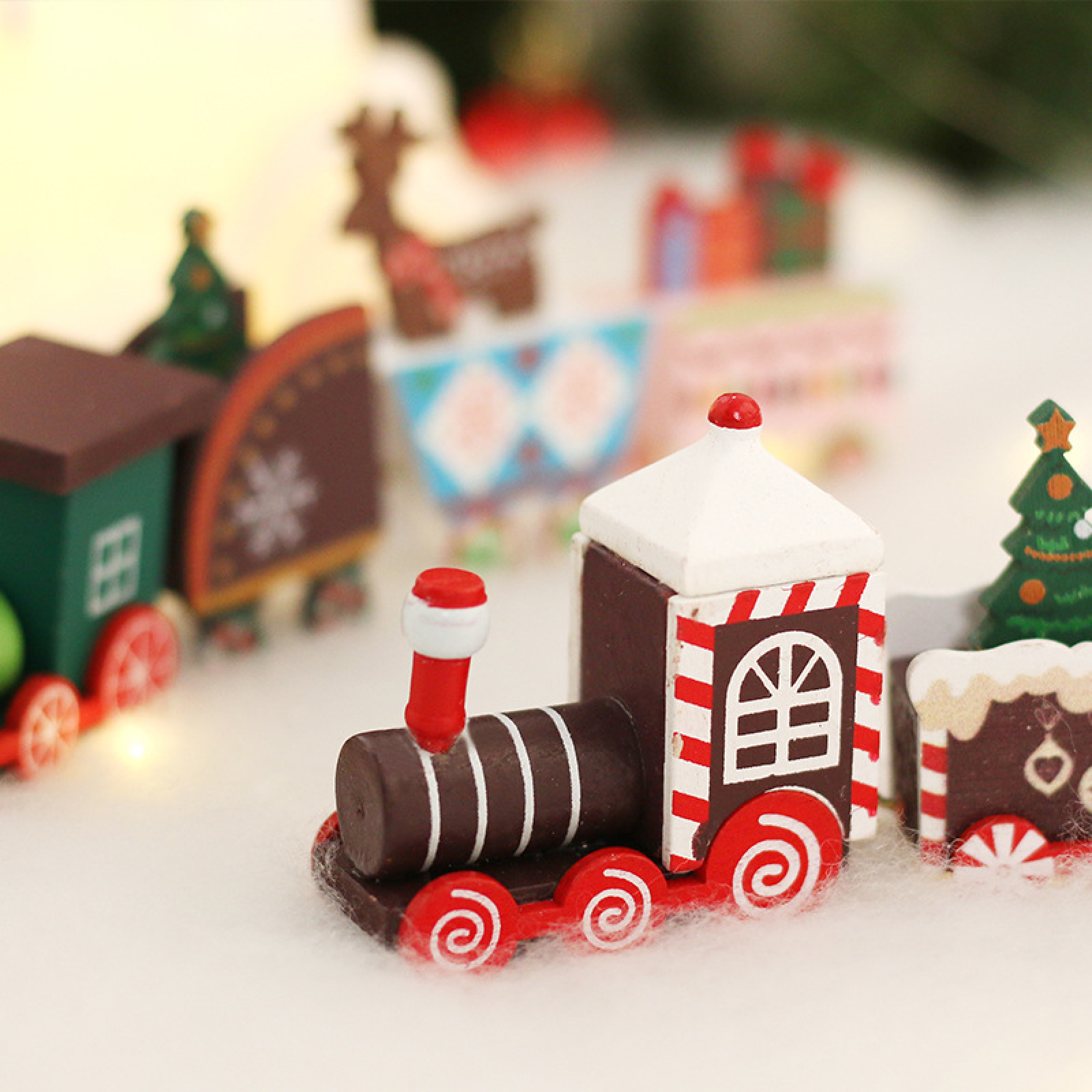 Ein buntes Holz-Weihnachtsspielzeugeisenbahn auf verschneiter Oberfläche.