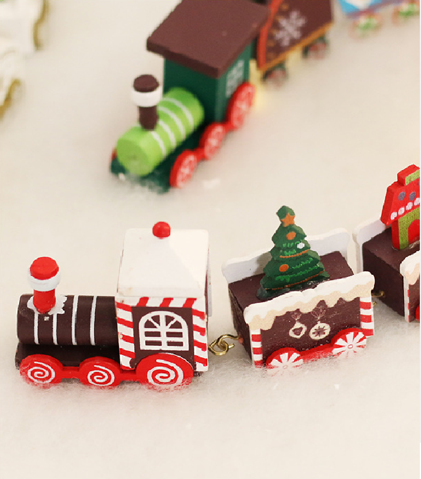 Holzspielzeugeisenbahn mit Weihnachtsmotiv im Schnee.