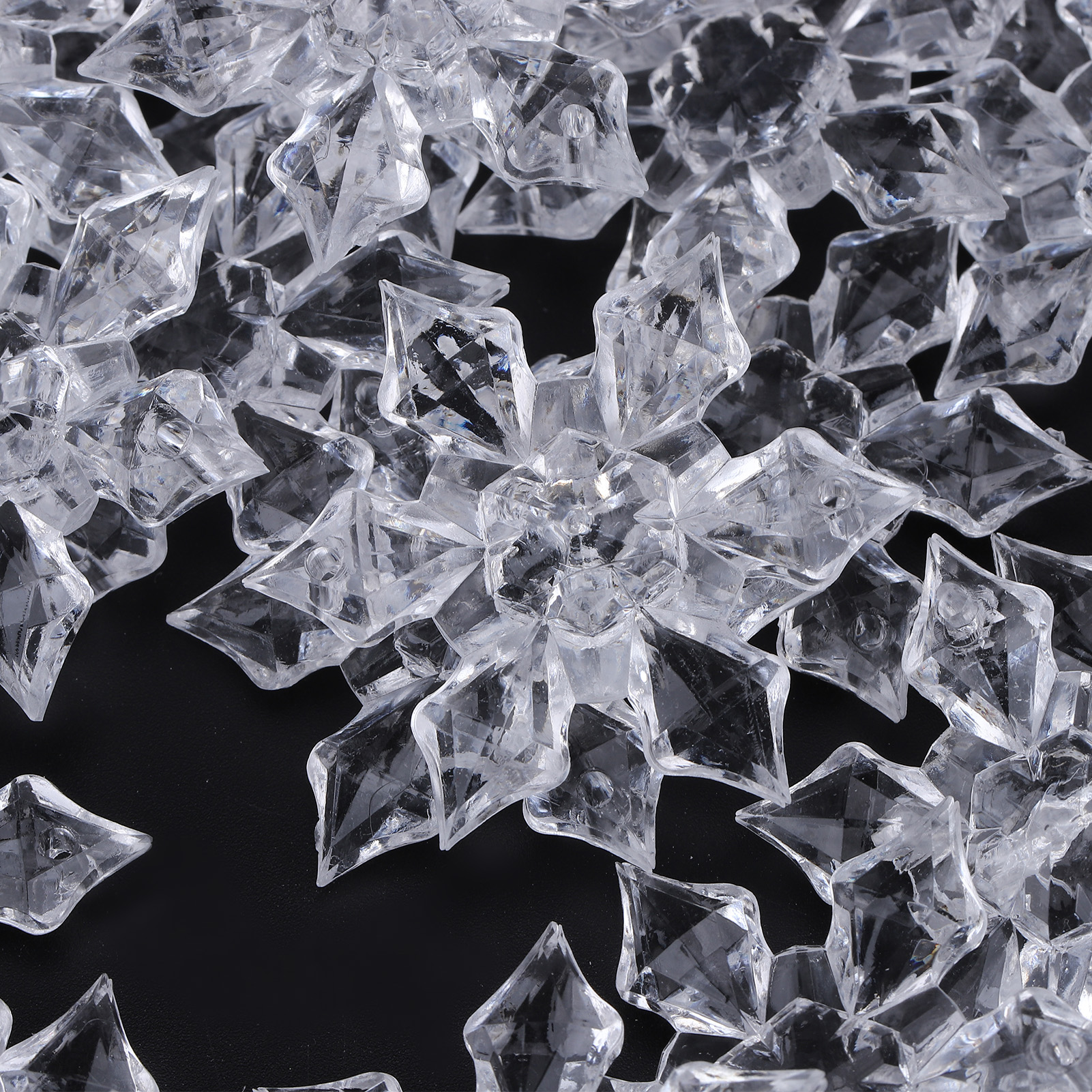 Glänzende, transparente Acryl-Eiskristalle oder Schneeflocken auf schwarzem Hintergrund.