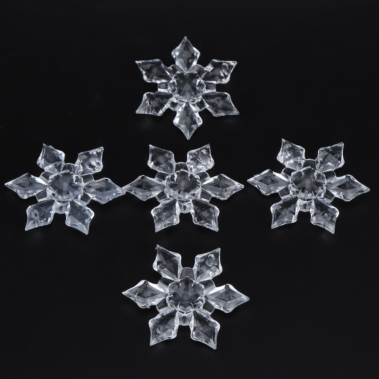 Fünf transparente, kristallähnliche Schneeflocken auf schwarzem Hintergrund.