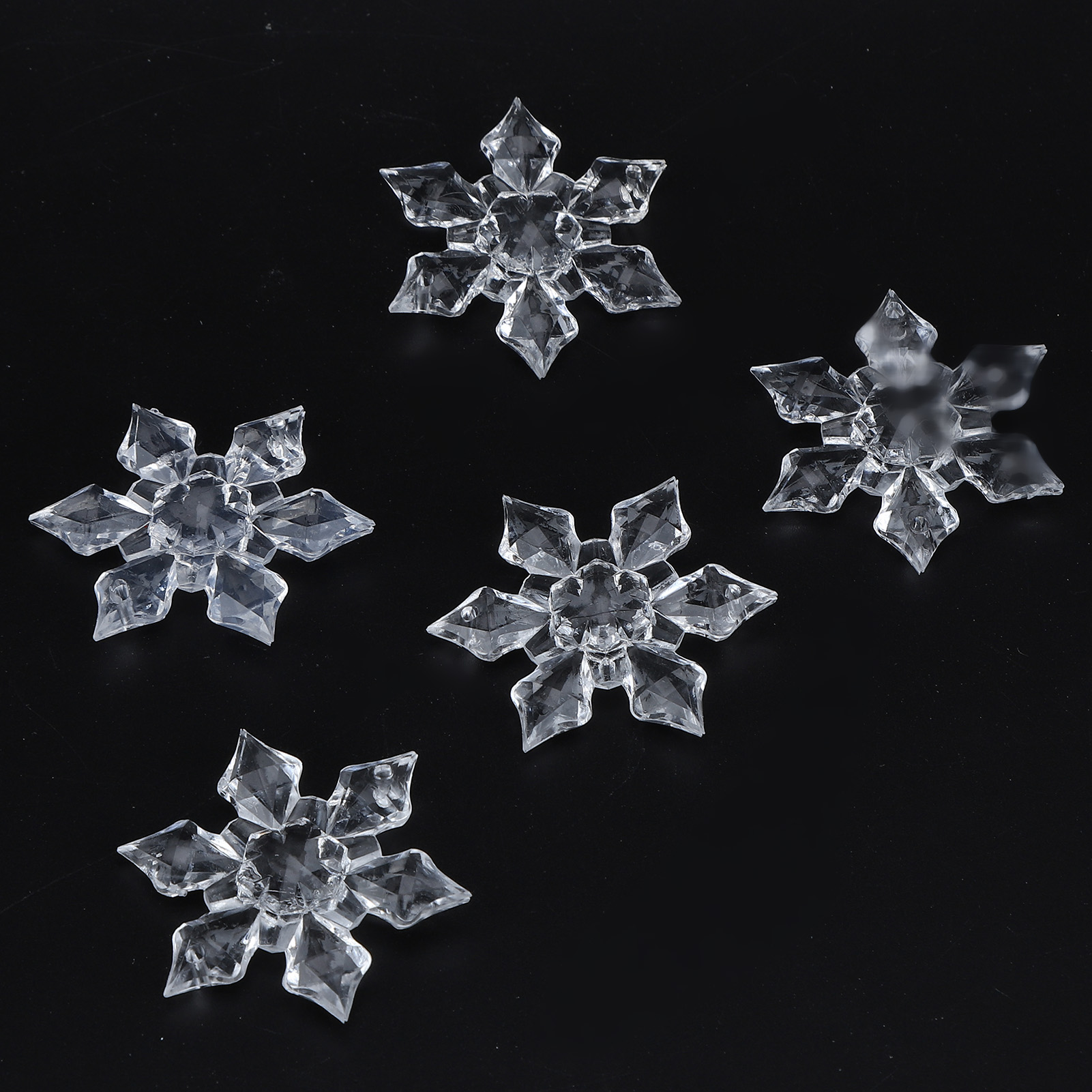 Fünf facettierte Kristall-Schneeflocken auf schwarzem Hintergrund.