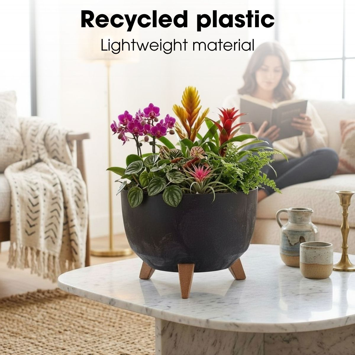 Un pot noir avec des plantes colorées sur une table en marbre blanc dans un salon lumineux.
