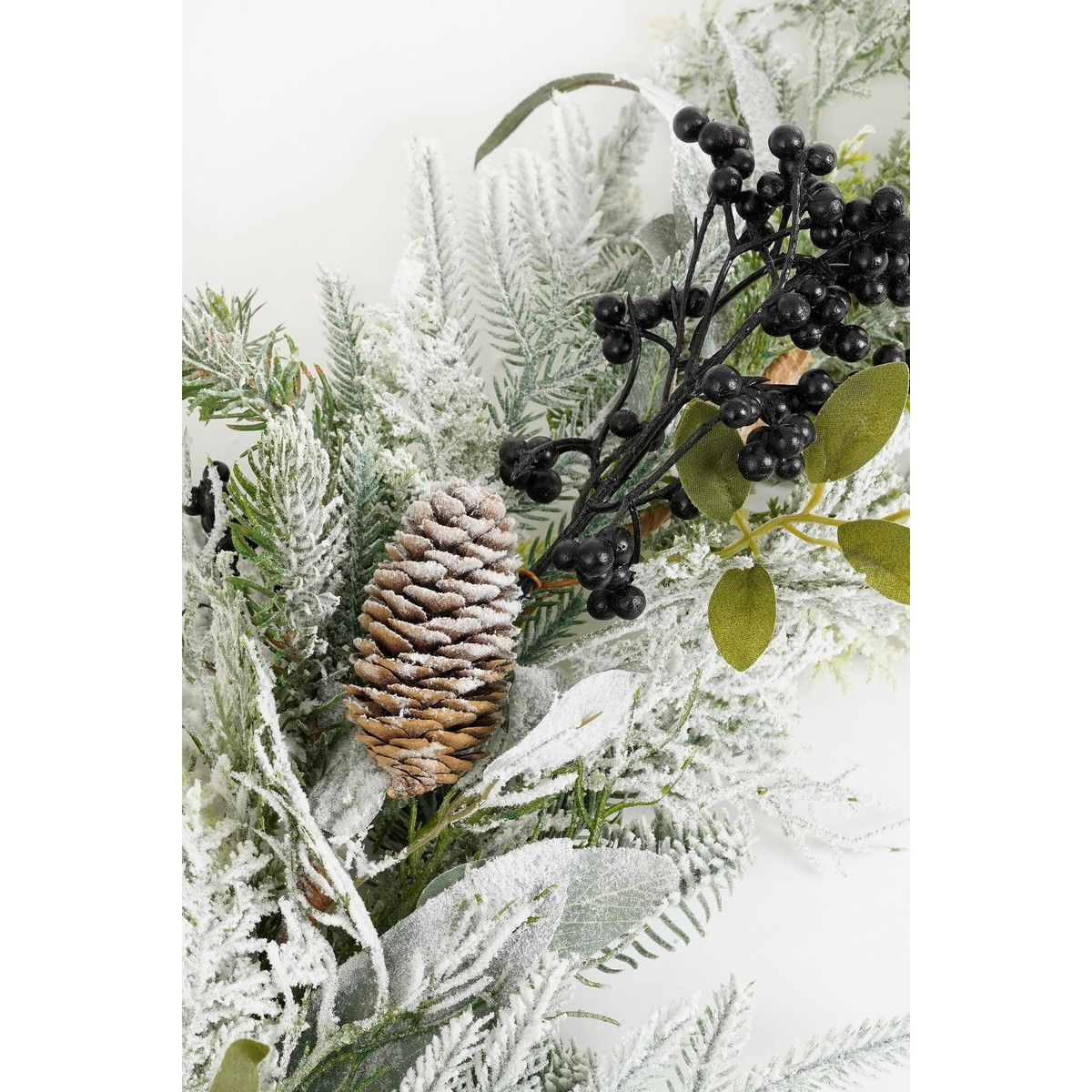 Sneeuwbedekte dennentakken met een dennenappel en zwarte bessen.
