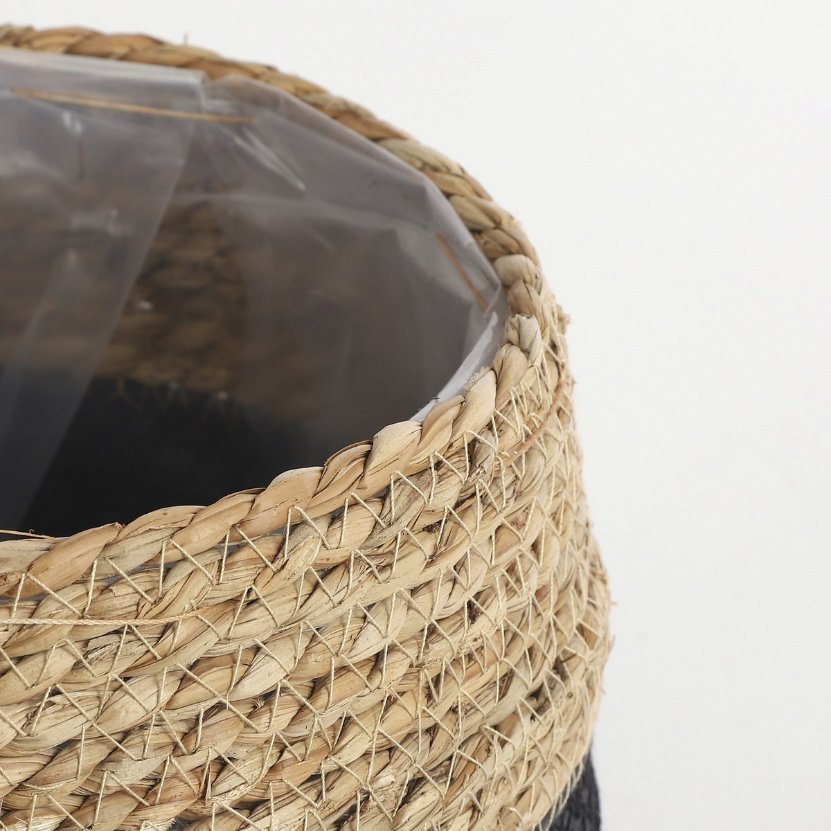 Gros plan d'un panier tressé avec une doublure en plastique sur fond blanc.