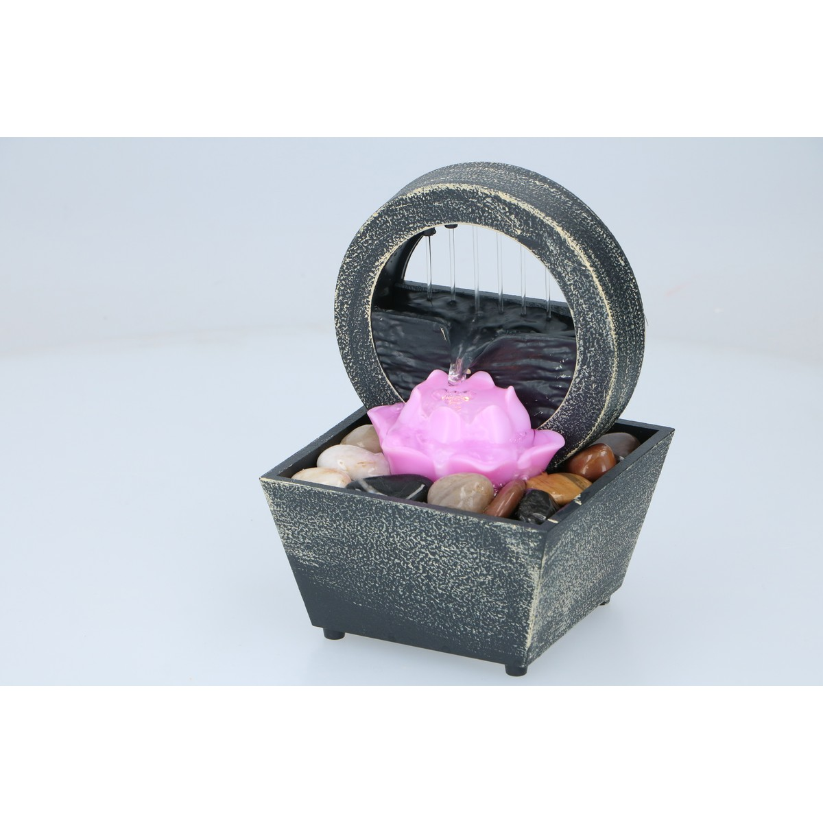 Een kleine tafelosfontein met een cirkelvormige ring en een roze lotusbloem, omringd door kleurrijke kiezels.