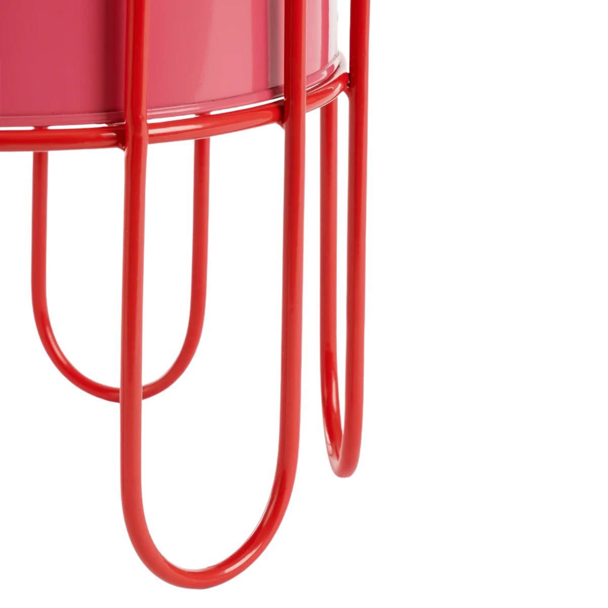 Un récipient rose repose sur un support métallique rouge sur fond blanc.