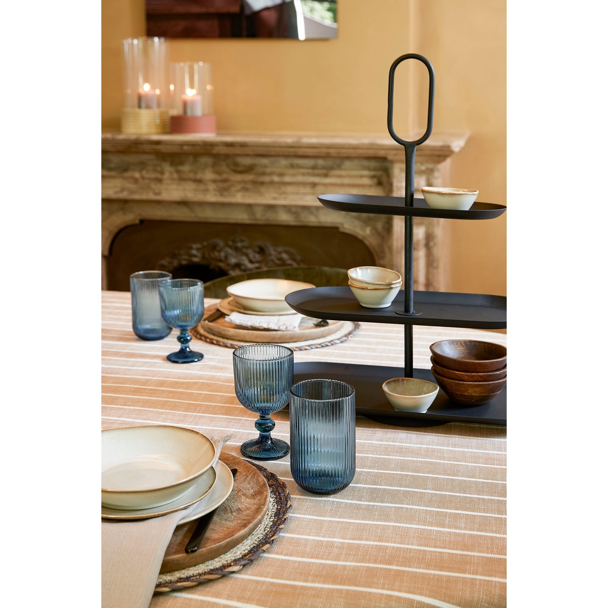 gedeckter Tisch mit gestreifter Tischdecke, blauem Glasgeschirr, Schalen und einer schwarzen Etagère