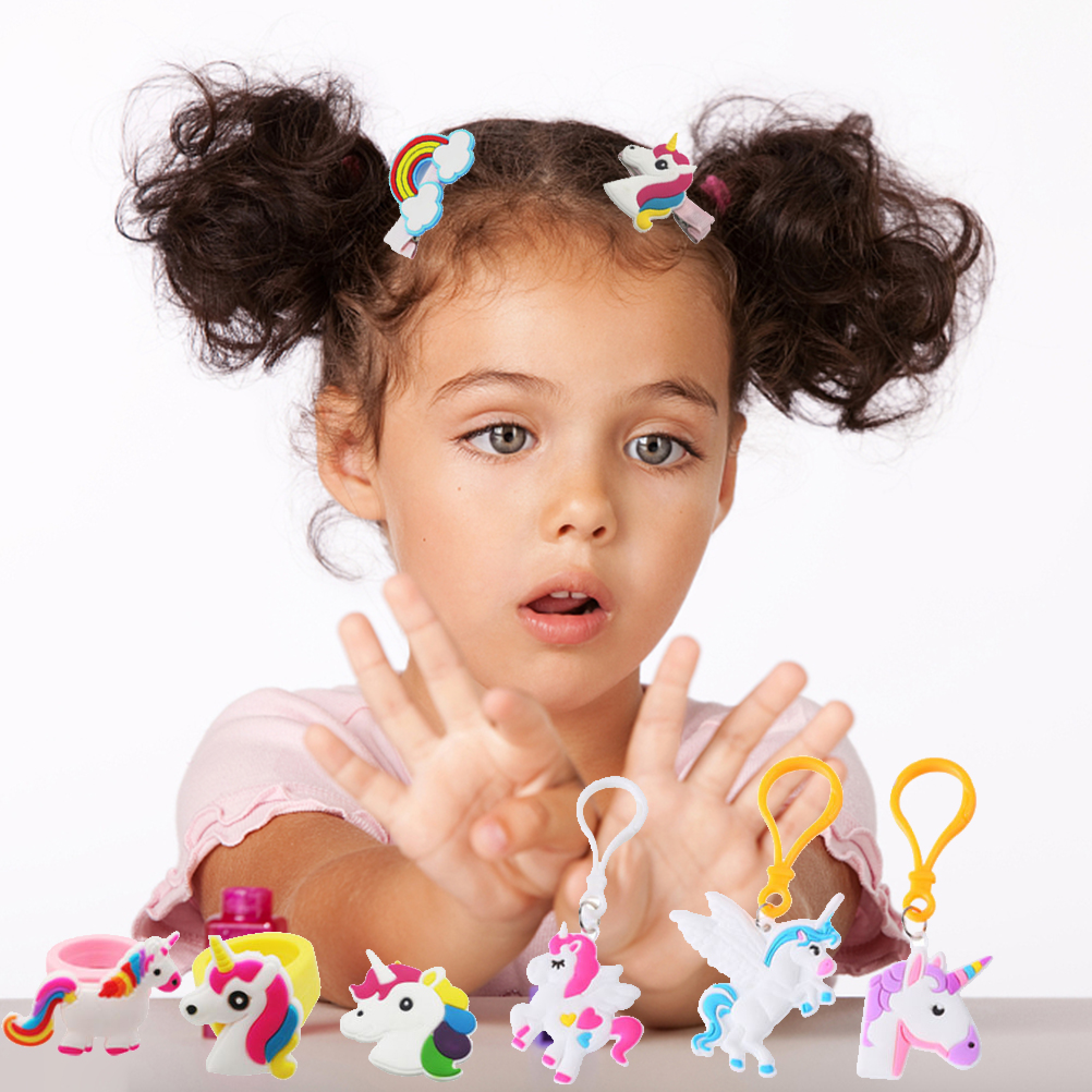 Ein kleines Mädchen mit Zöpfen zeigt überrascht auf bunte Einhorn-Spielzeuge.