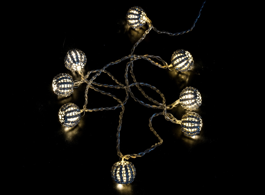 Una cadena de luces LED esféricas, decorativas y plateadas sobre un fondo negro.