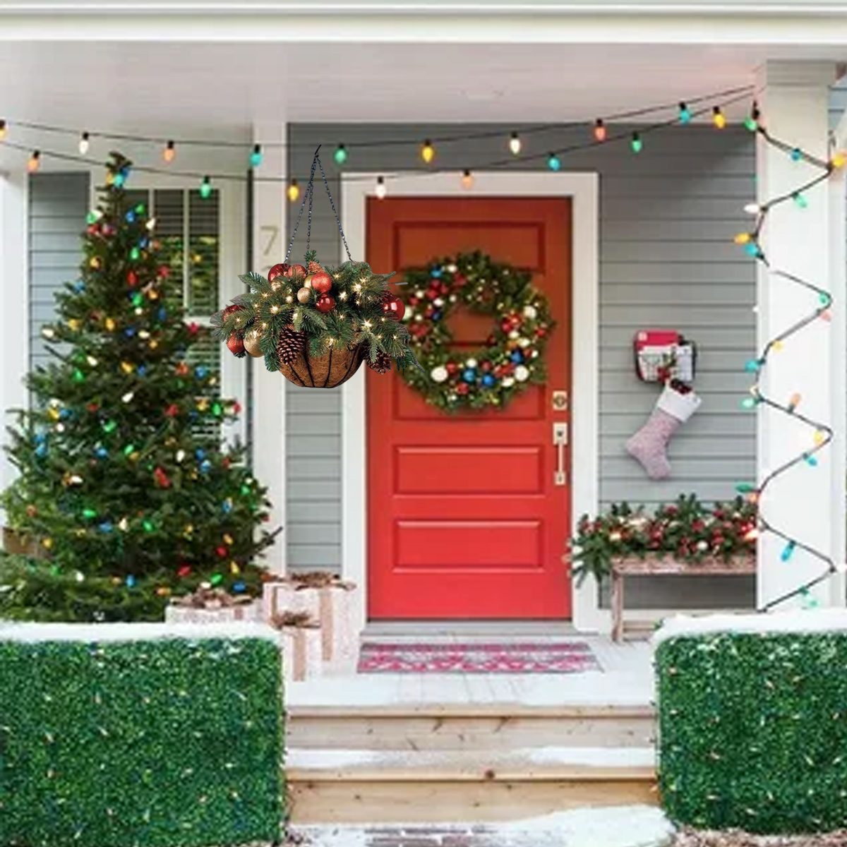 Geschmücktes Haus zu Weihnachten mit roter Tür, Kranz, hängendem Korb und beleuchtetem Baum.