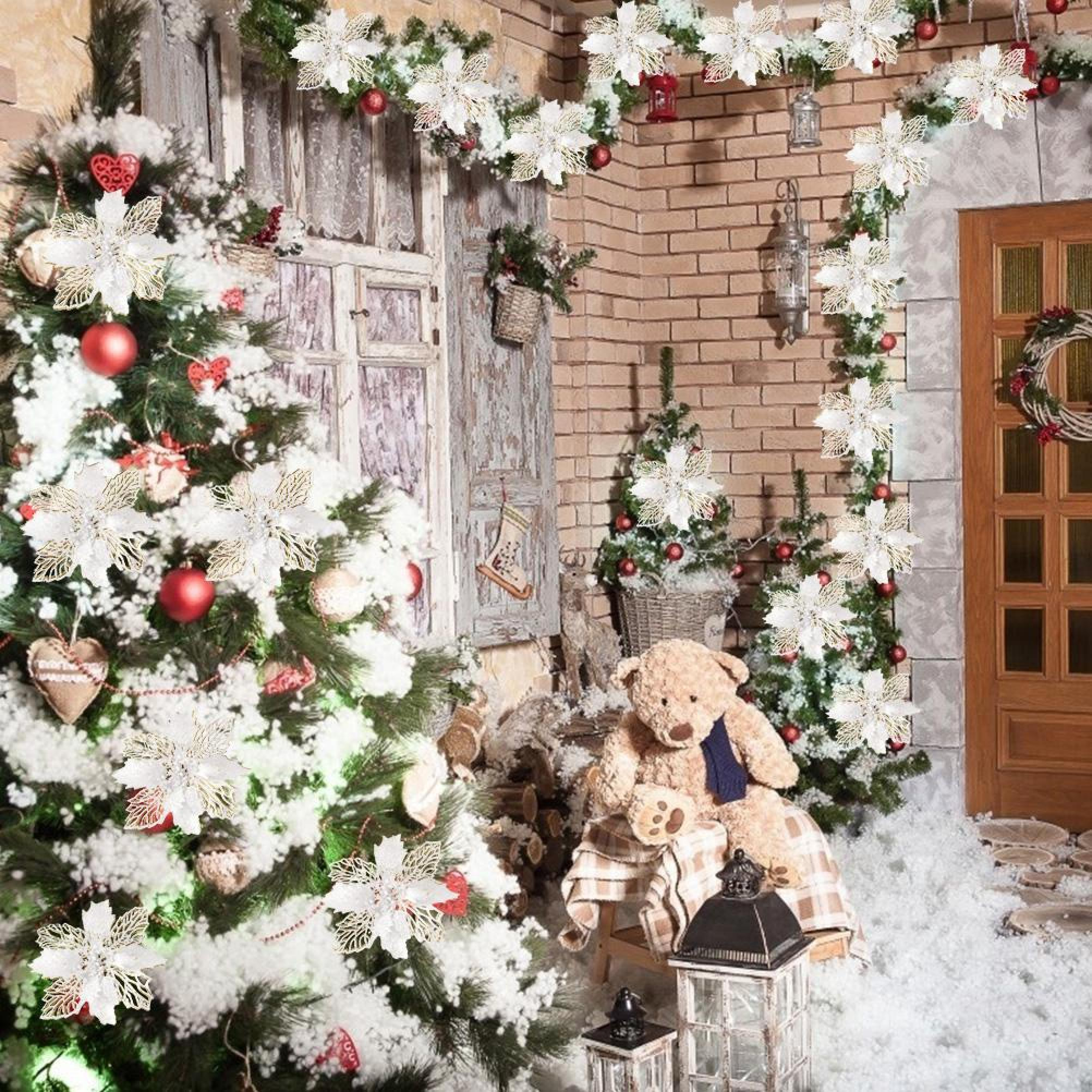 Festliche Veranda mit schneebedeckten Weihnachtsbäumen, weißen Weihnachtssternen, einem Teddybären und Laternen.