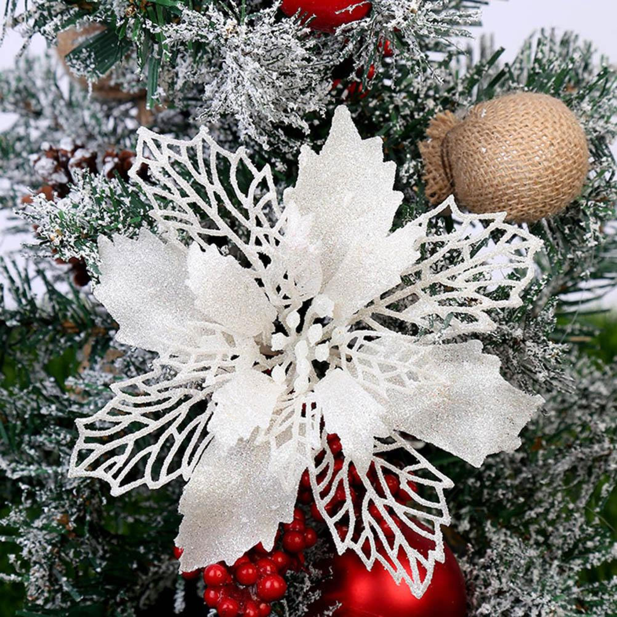 Glitzernde weiße Weihnachtsstern-Dekoration auf schneebedeckten Tannenzweigen mit roten Beeren.