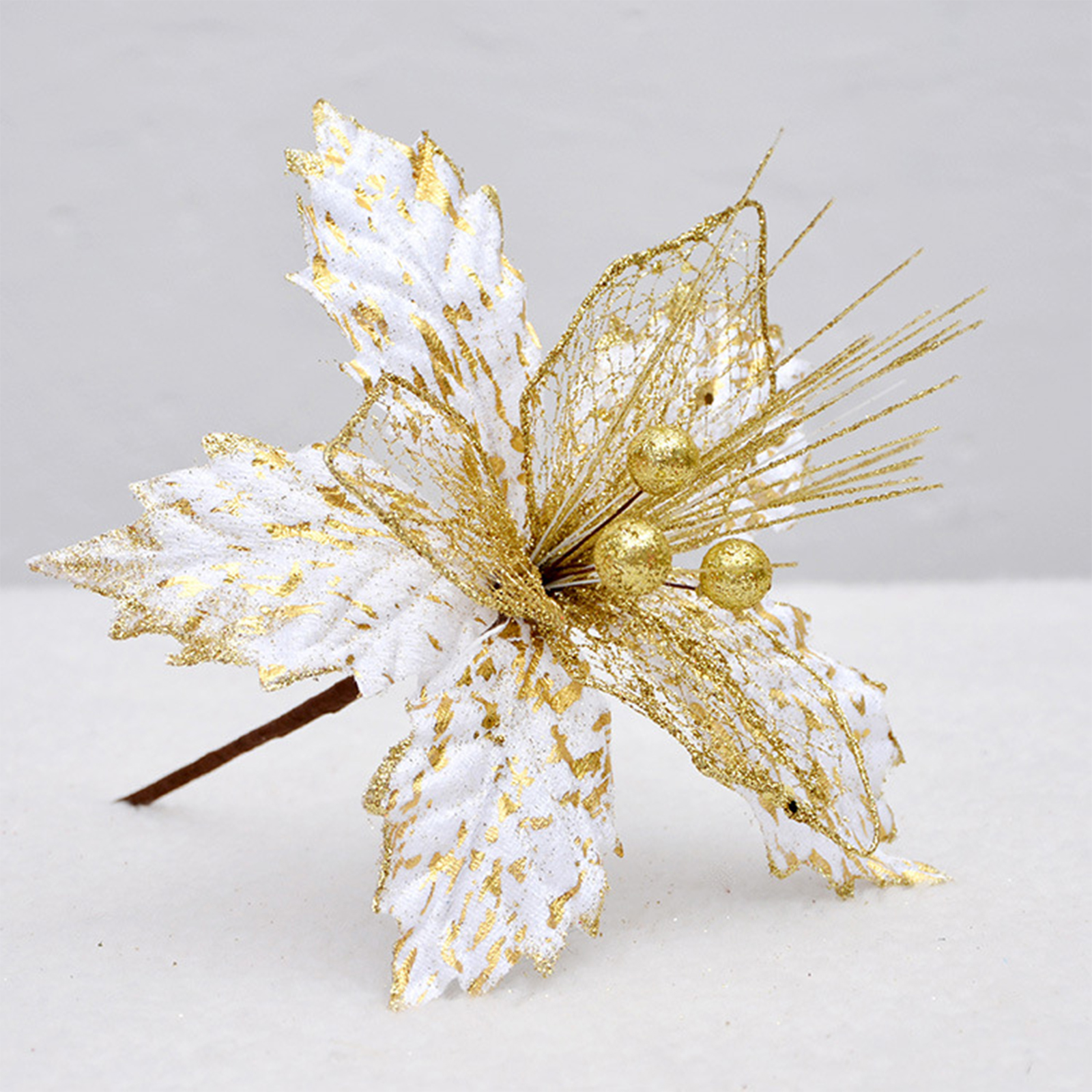 Eine dekorative weiße und gold glitzernde Kunstblume mit Beeren auf hellem Grund.