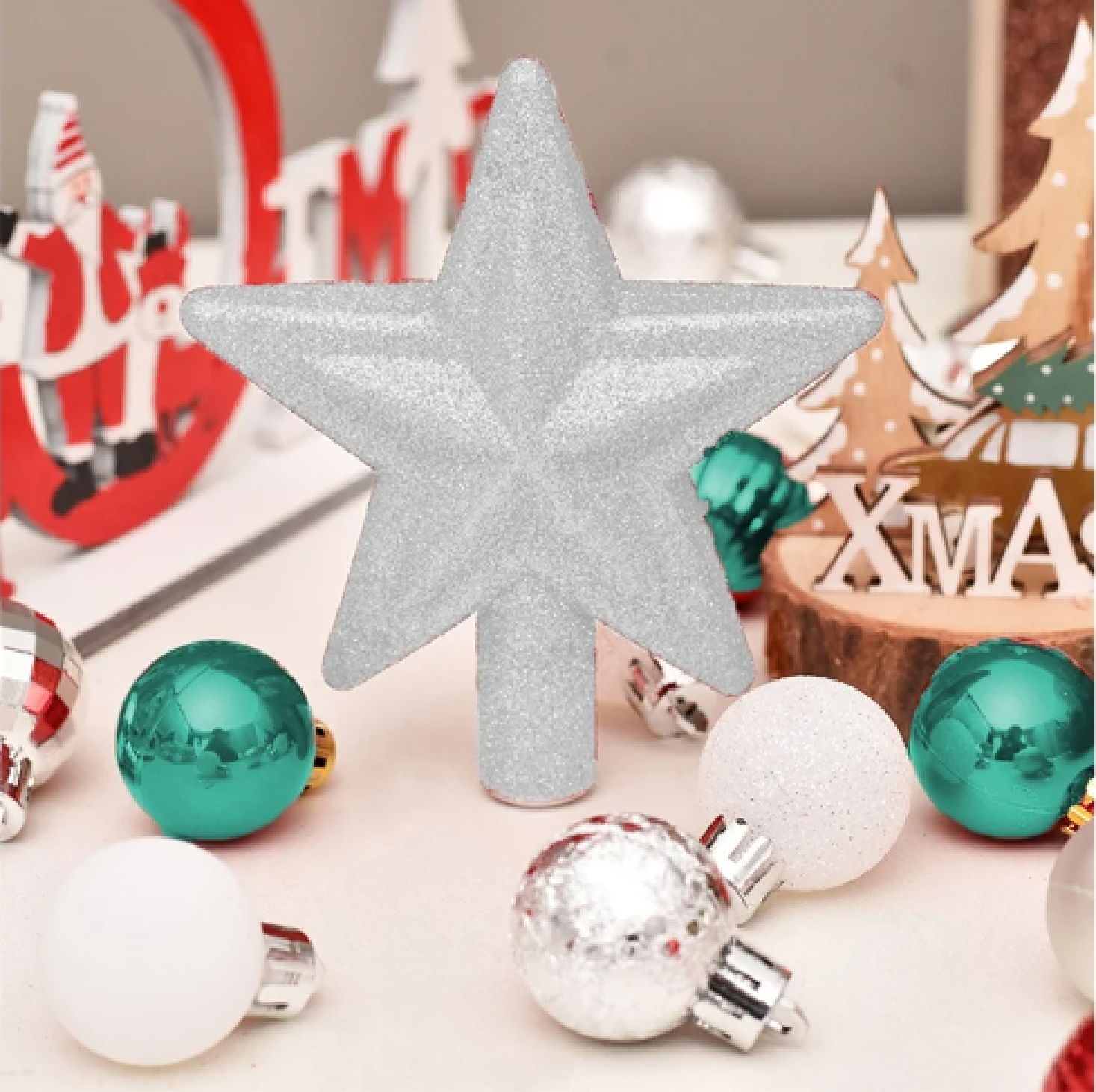Ein glitzernder silberner Baumspitzenstern steht umgeben von türkisen und weißen Weihnachtskugeln und Dekorationen.