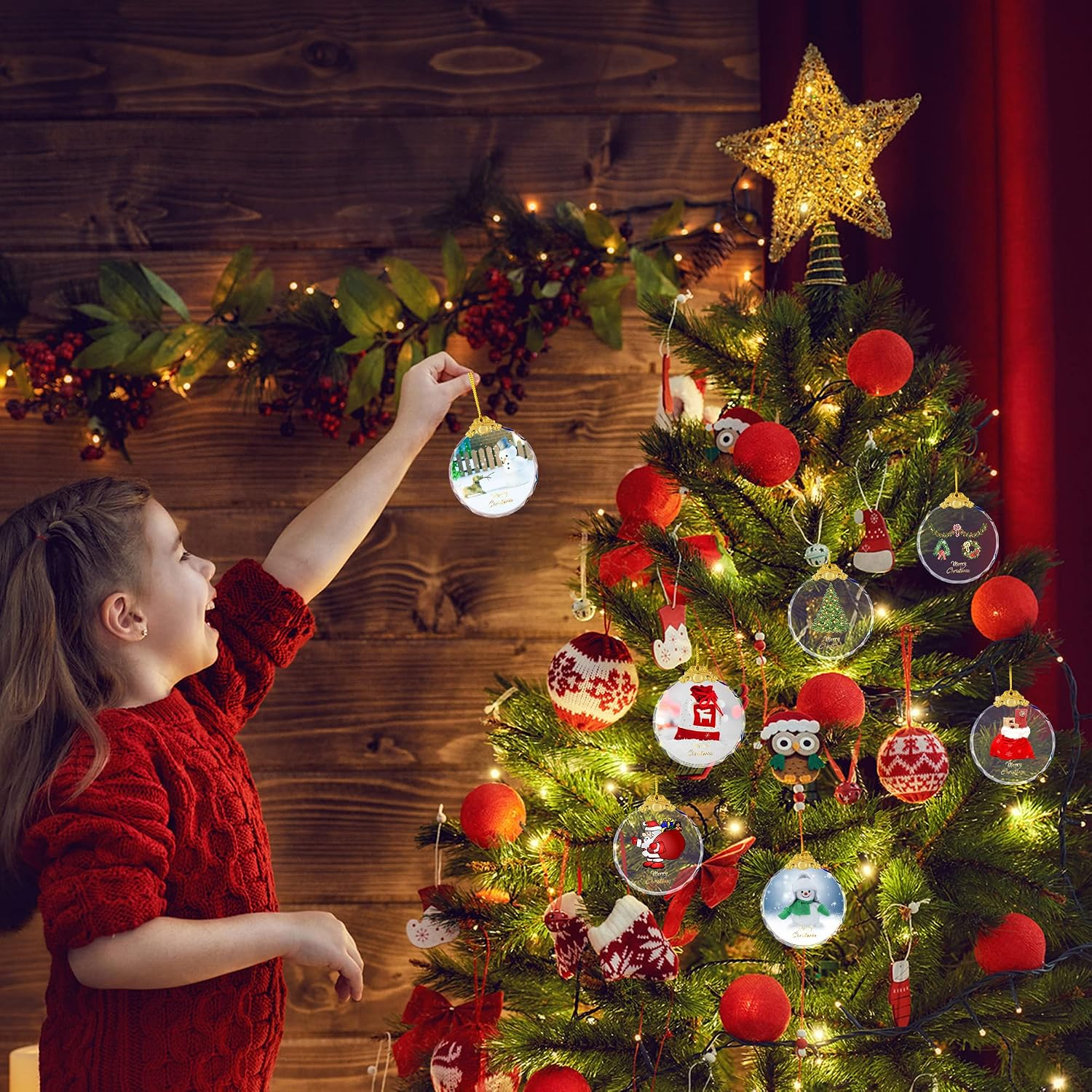 Ein Mädchen in einem roten Pullover hängt eine Weihnachtskugel an einen leuchtenden Tannenbaum.