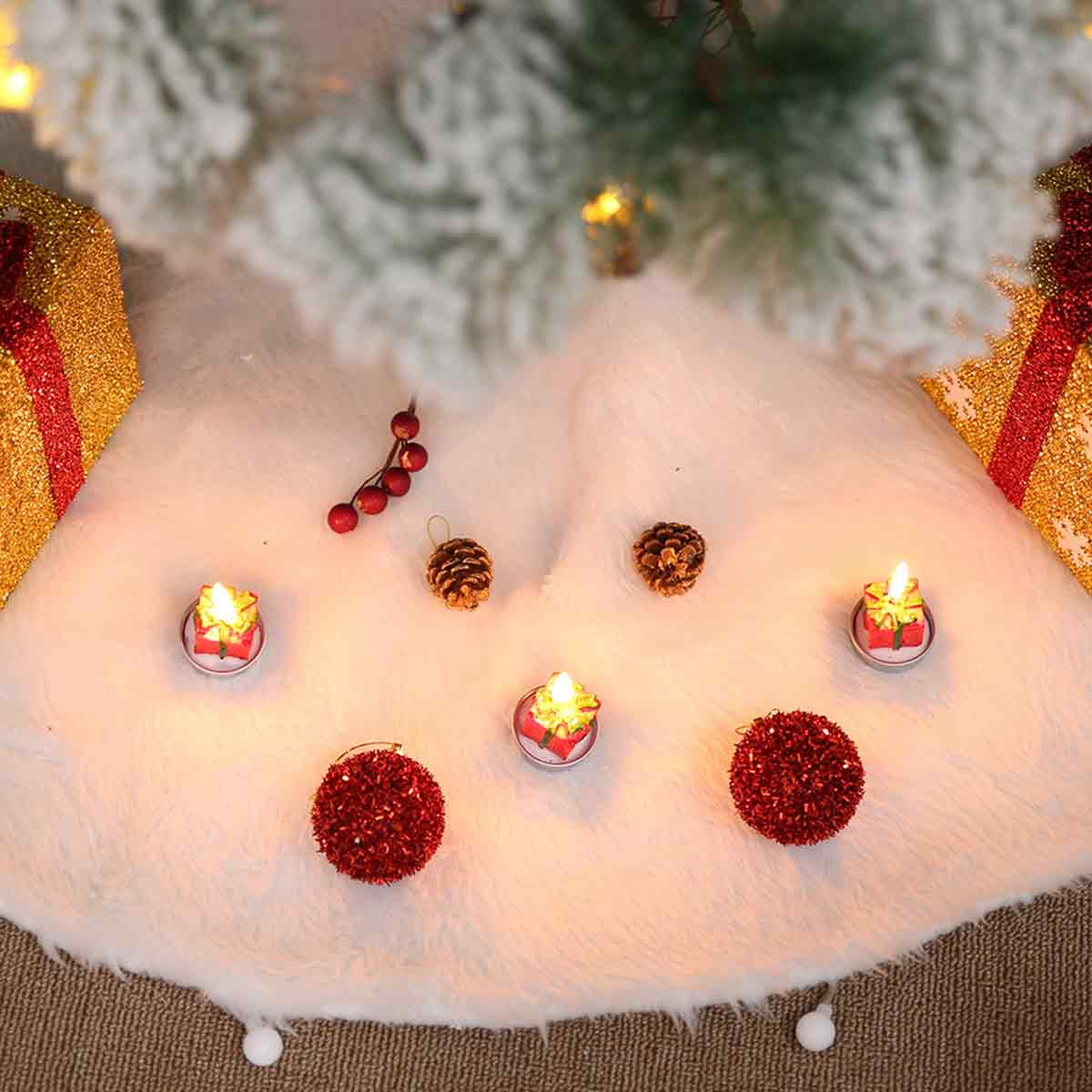 Weihnachtsbaumrock in Weiß mit Geschenken, roten Kugeln, Tannenzapfen und kleinen Geschenkkerchen.