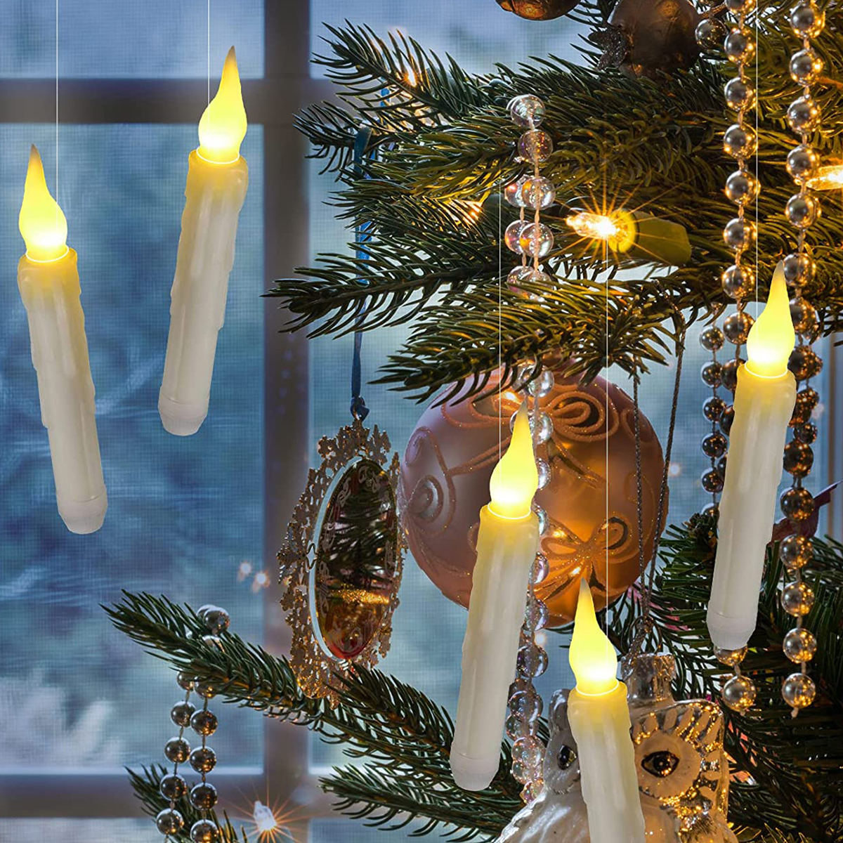 Schwimmende elektrische Kerzen hängen an silbernen Fäden vor einem geschmückten Weihnachtsbaum mit Kugeln.
