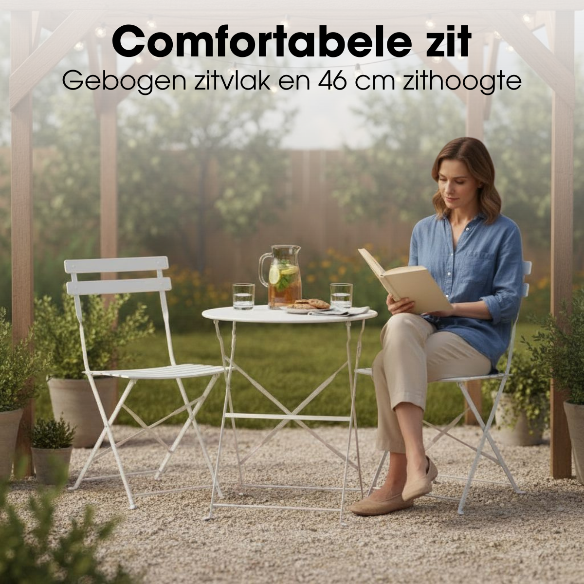 Eine Frau sitzt auf einem weißen Gartenstuhl im Freien, liest ein Buch und hat einen Tisch mit Getränken vor sich.