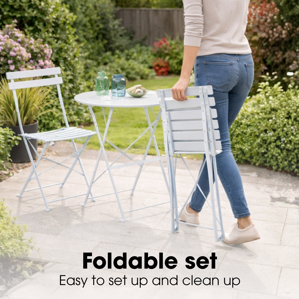 Eine Frau in Jeans stellt einen klappbaren Gartenstuhl an einen Tisch im Garten.