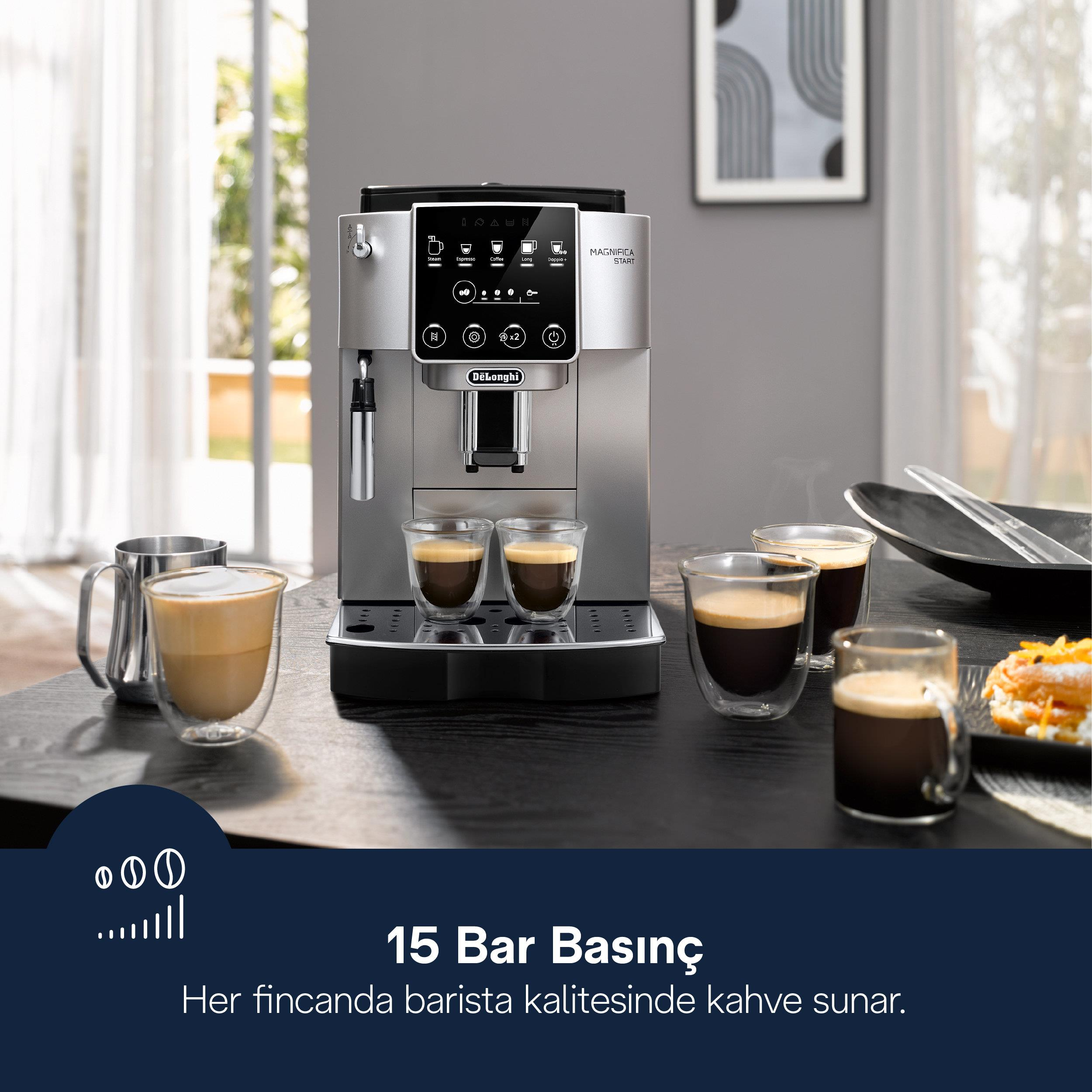 Dolu bardaklar ve bir tabak tatlı ile masada duran gümüş rengi DeLonghi kahve makinesi.