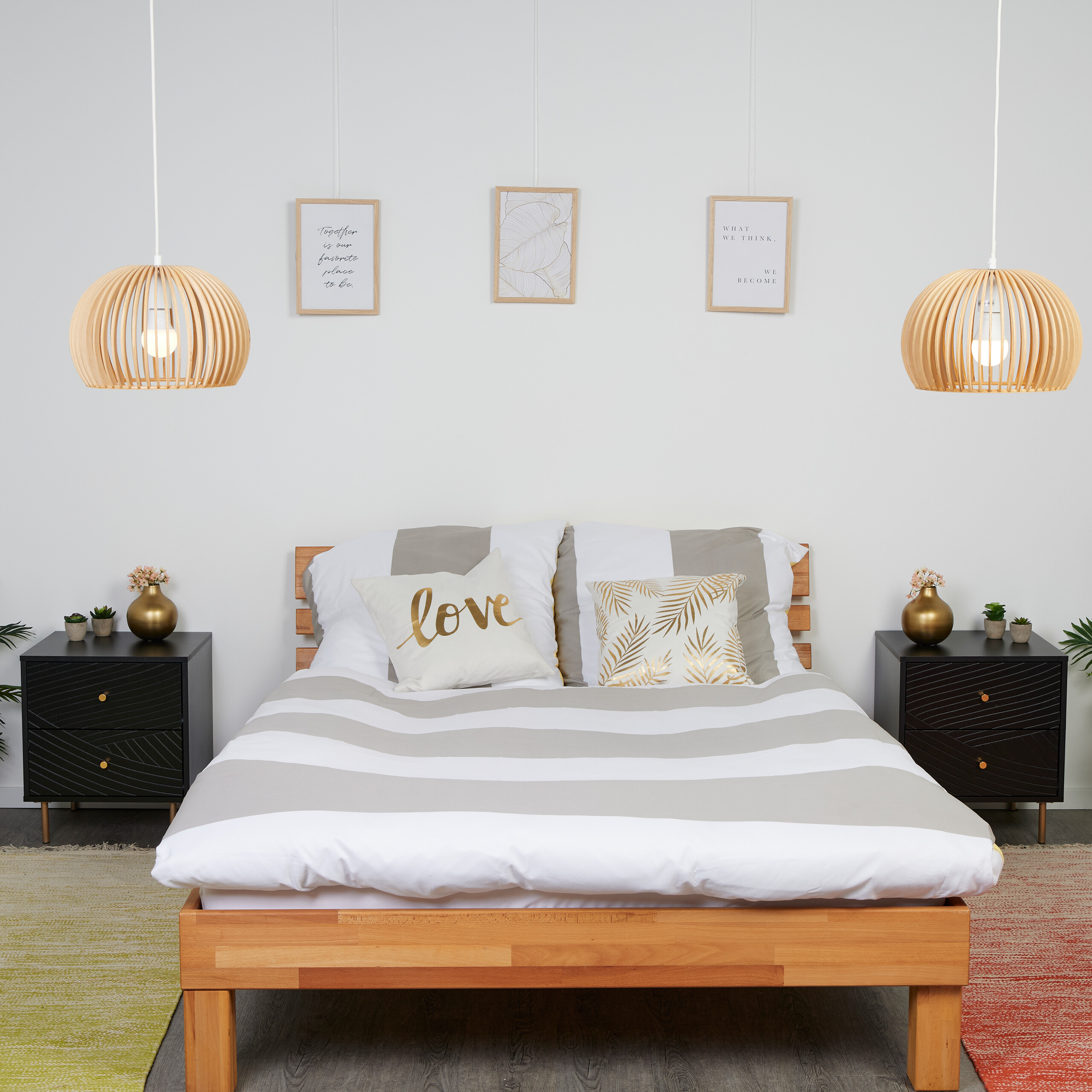 Schlafzimmer mit Holzbett, grau-weiß gestreifter Bettwäsche, schwarzen Nachttischen und Holzpendelleuchten.