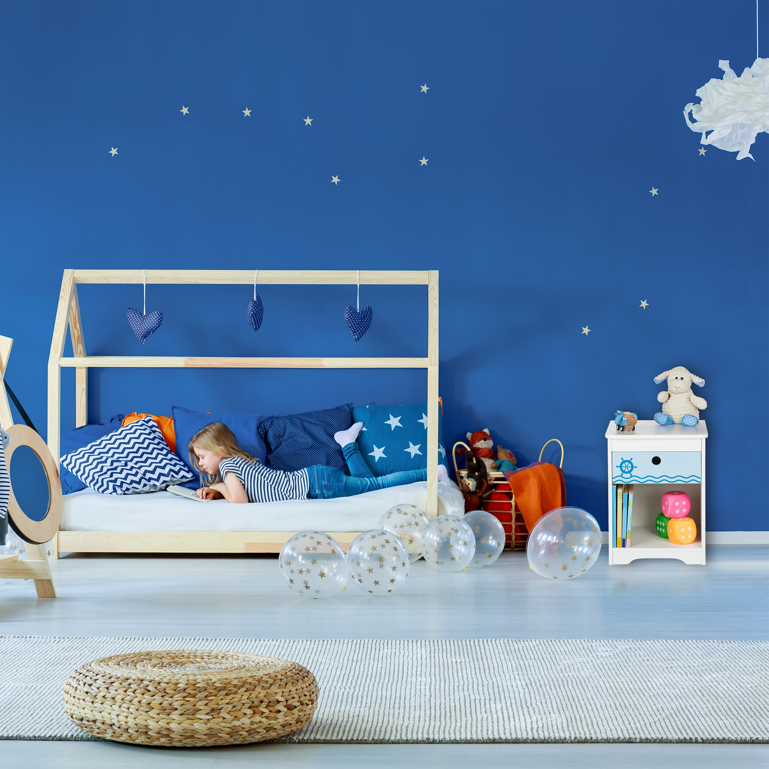 Ein blondes Mädchen liegt auf einem Holzbett in einem blau gestrichenen Zimmer mit Sternenaufklebern und liest.