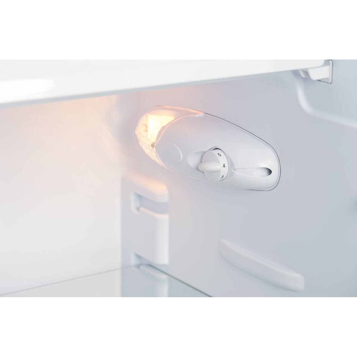 Interior iluminado de un refrigerador blanco con un selector de temperatura.
